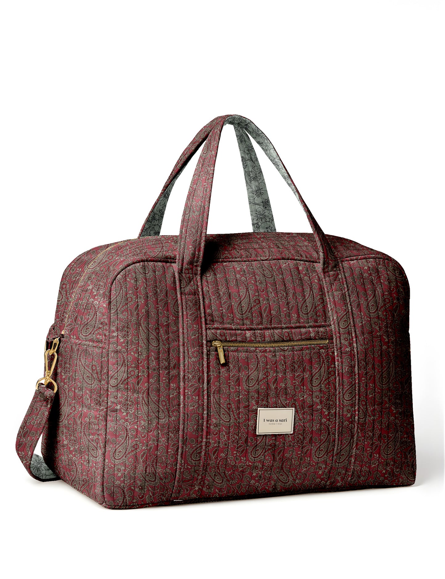 Brown quilted duffle bag with paisley pattern, front zip pocket, dual handles, and label reading "I was a sari"