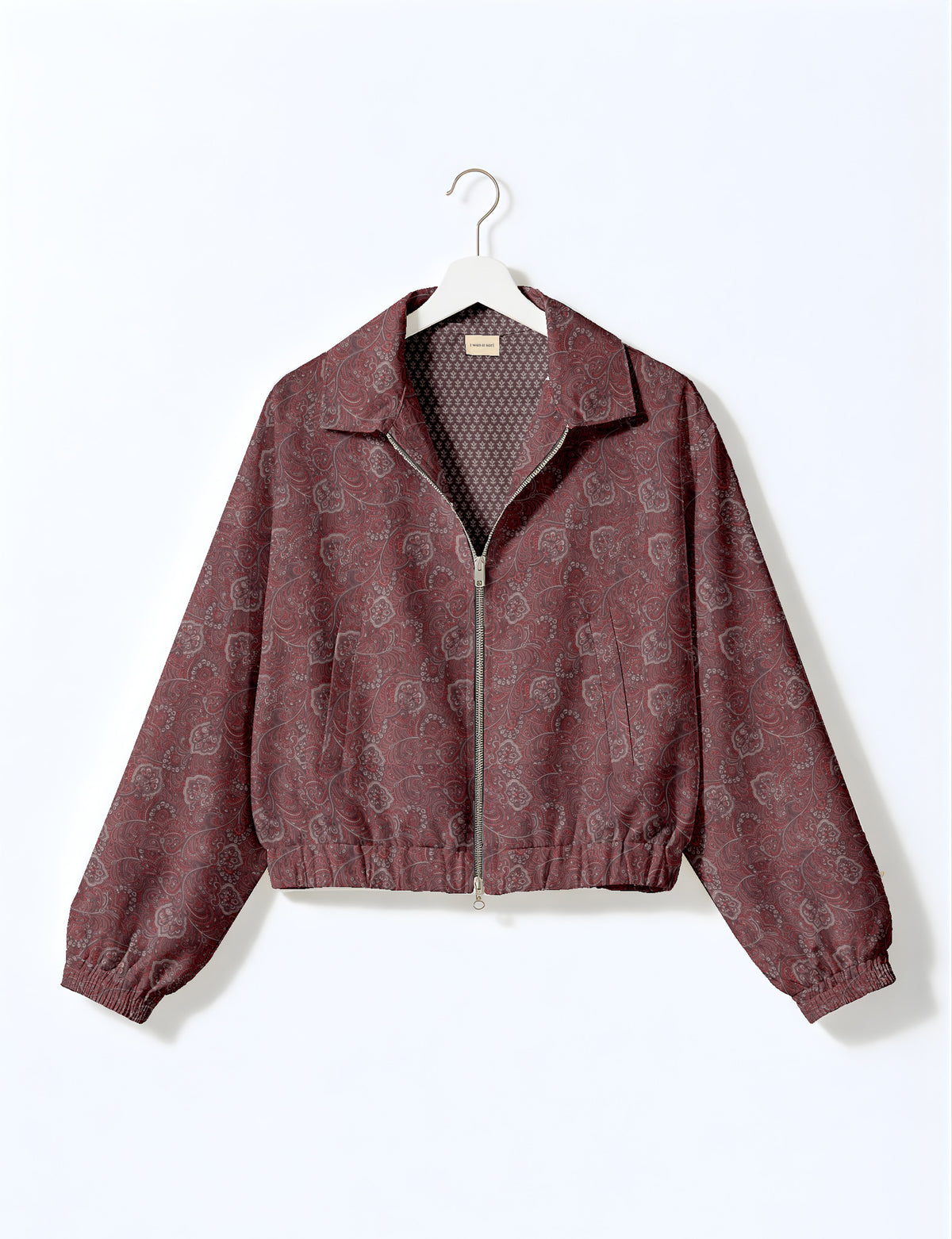 Brown floral bomber jacket with front zipper, elastic cuffs and hem, hanging on white hanger, red floral inner lining visible