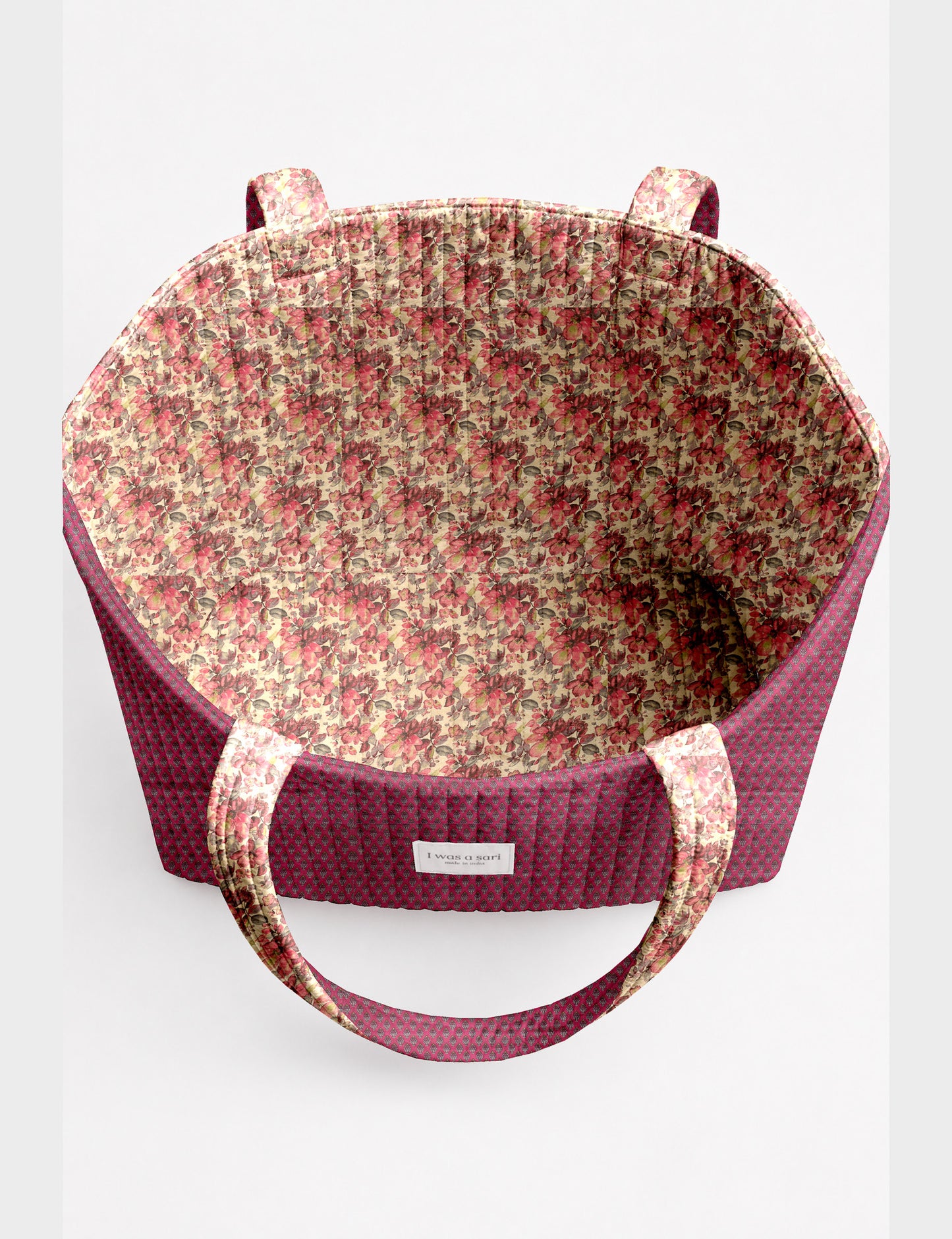 Quilted beach bag with yellow tropical exterior and red patterned interior, shown from top view with handles visible