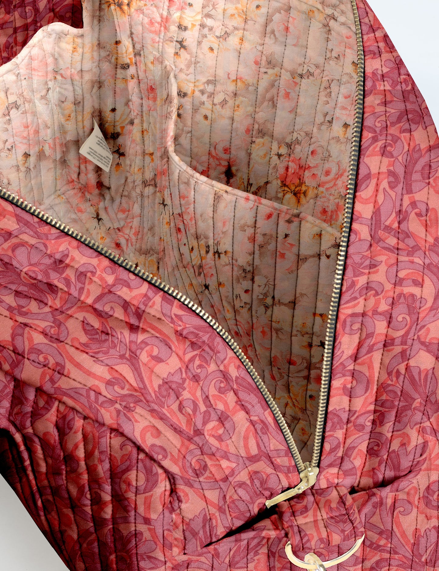 Quilted duffle bag in pink with tropical floral pattern, gold zipper, and interior floral lining with pocket