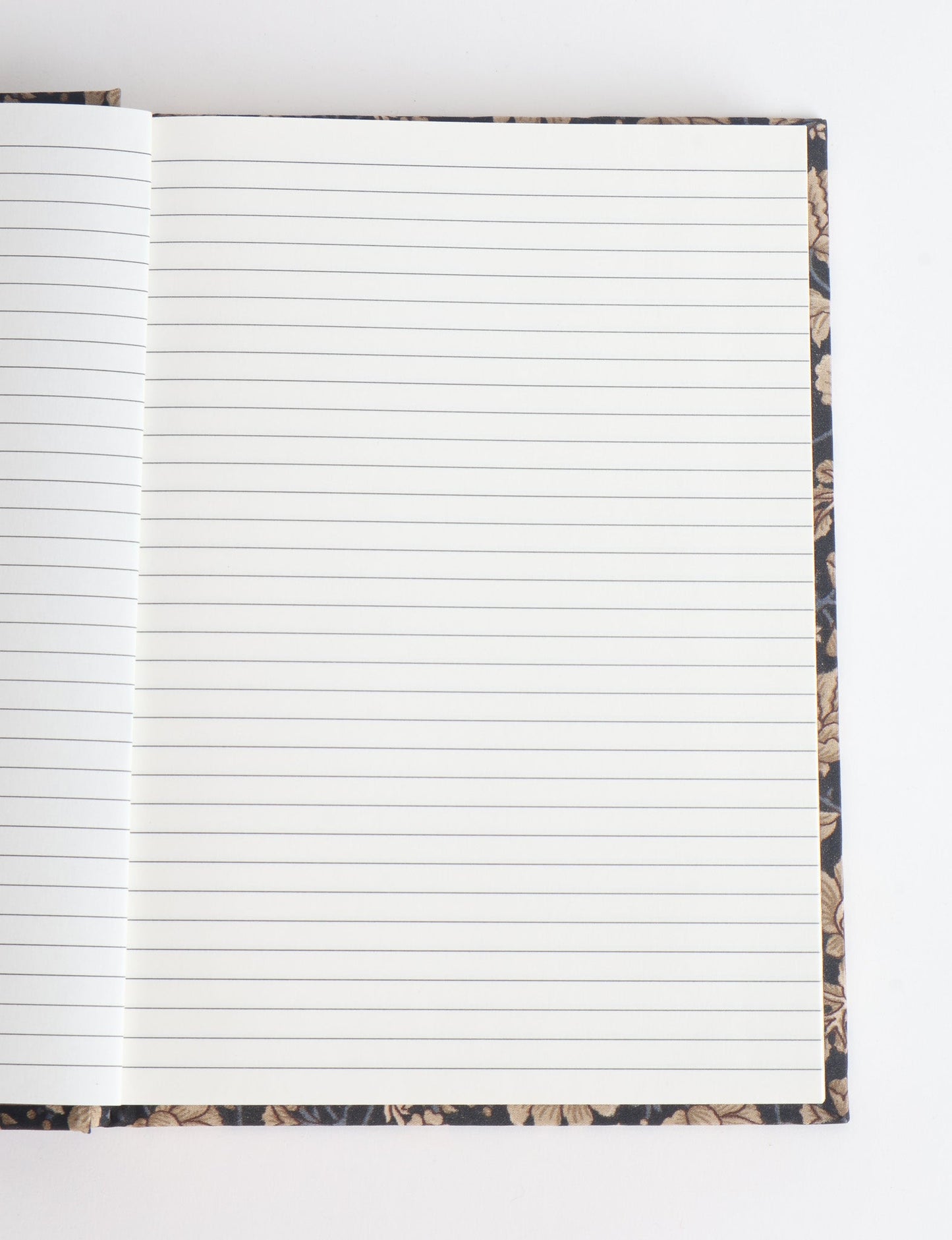 A5 hard cover notebook with green floral fabric cover, open to blank grid pages, flat lay view on white background