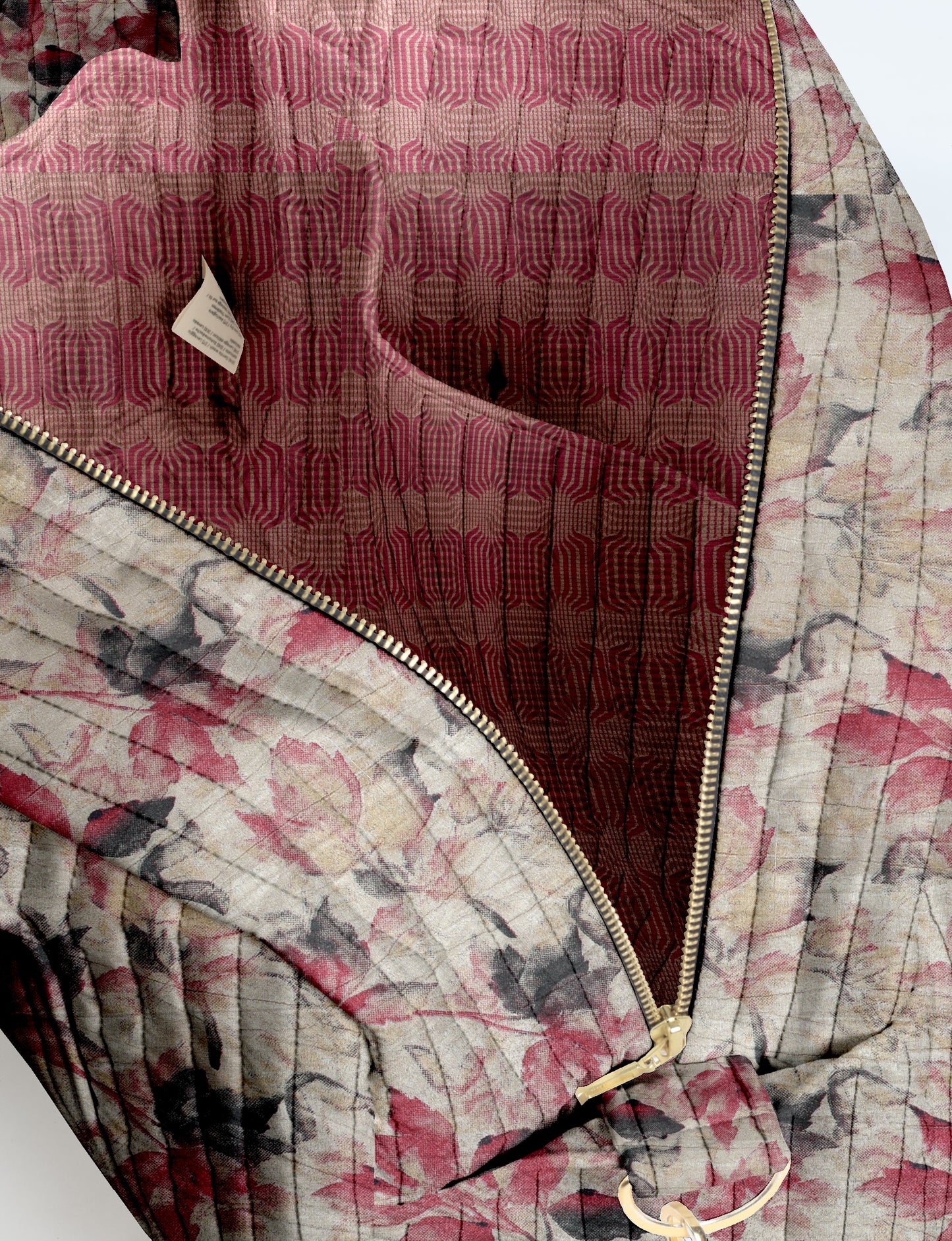 Quilted duffle bag with beige, pink, and black leaf pattern, gold zipper, and red geometric patterned interior lining