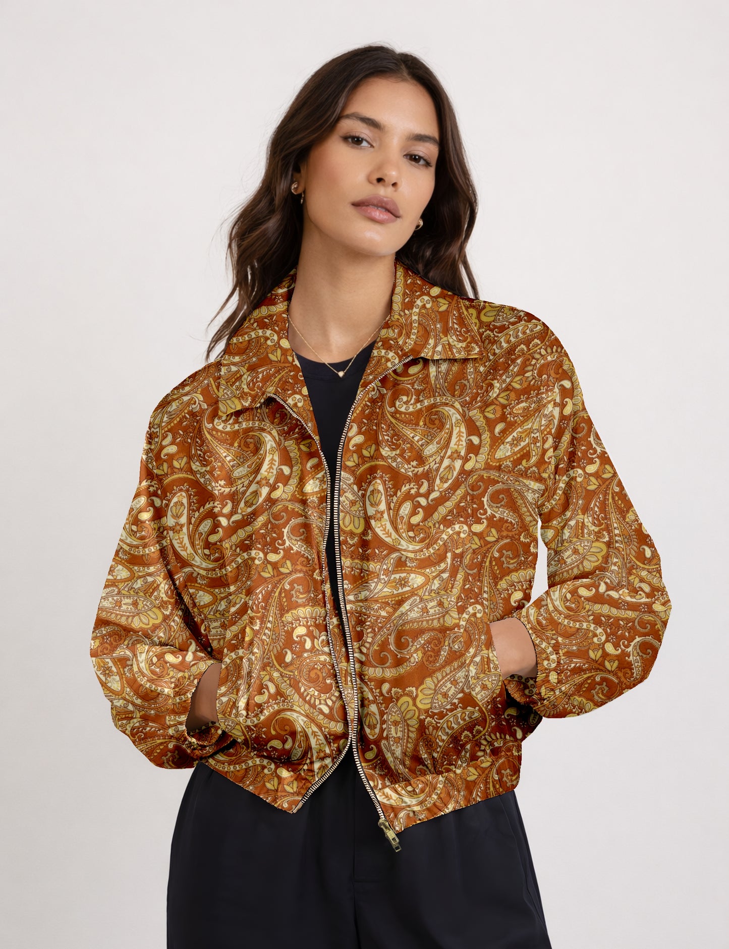 Woman wearing yellow and brown paisley patterned bomber jacket with front zipper and side pockets, paired with black pants