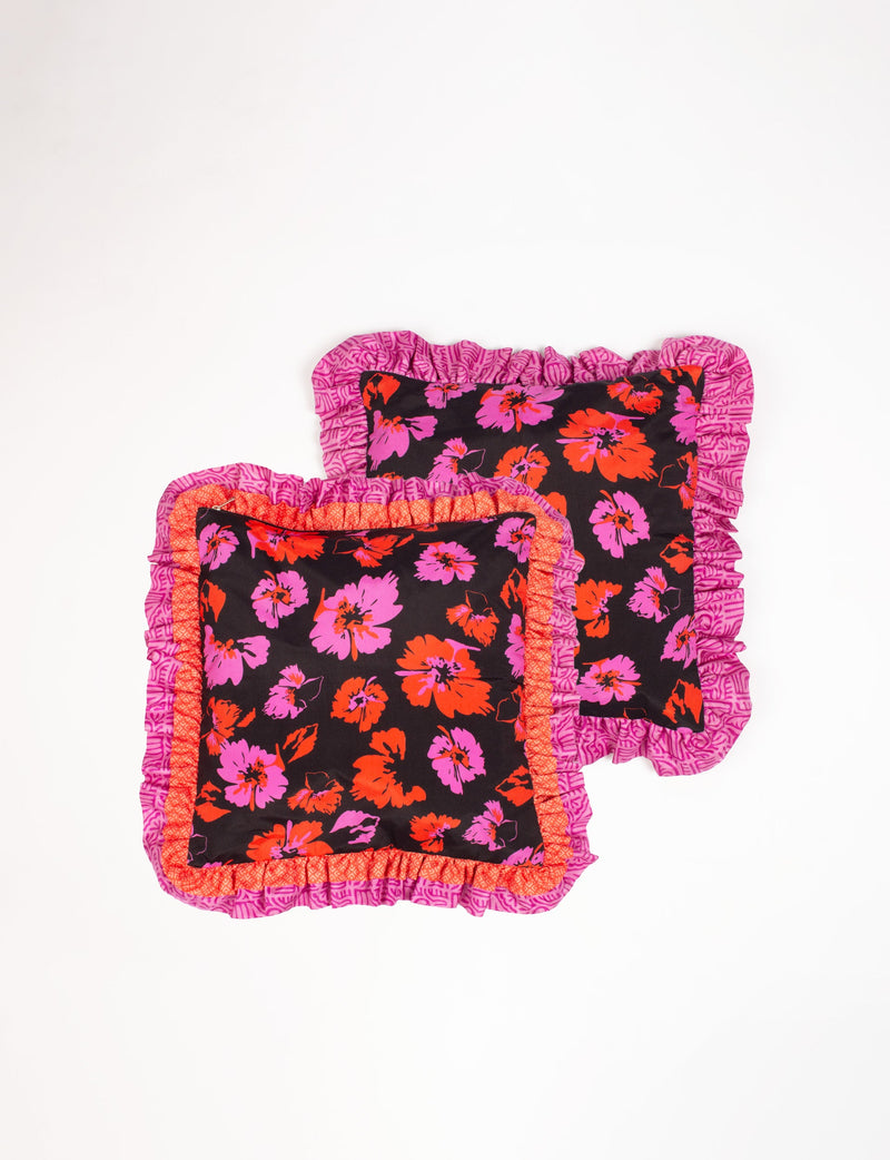 Set of two black cushion covers with red and pink floral print and double frill edges in pink and orange patterns, flat lay