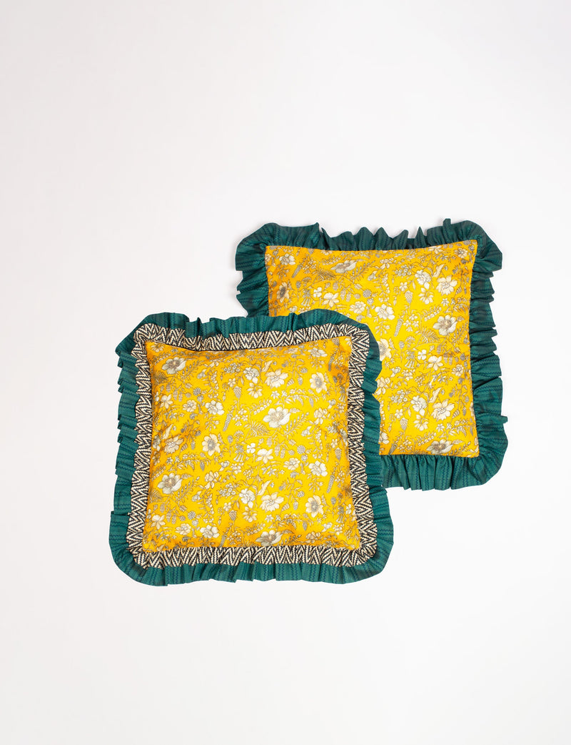 Set of two yellow floral cushion covers with double frill edges in dark green and black-and-white zigzag pattern, flat lay