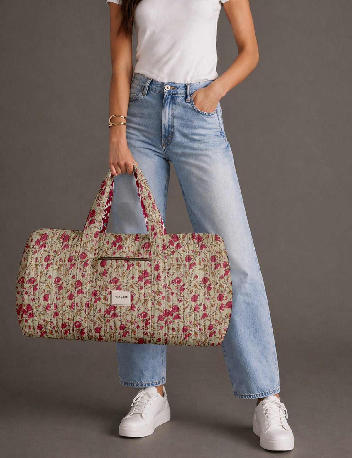 Quilted brown paisley barrel bag with double handles, front pocket, and gold zipper, shown in side angle view