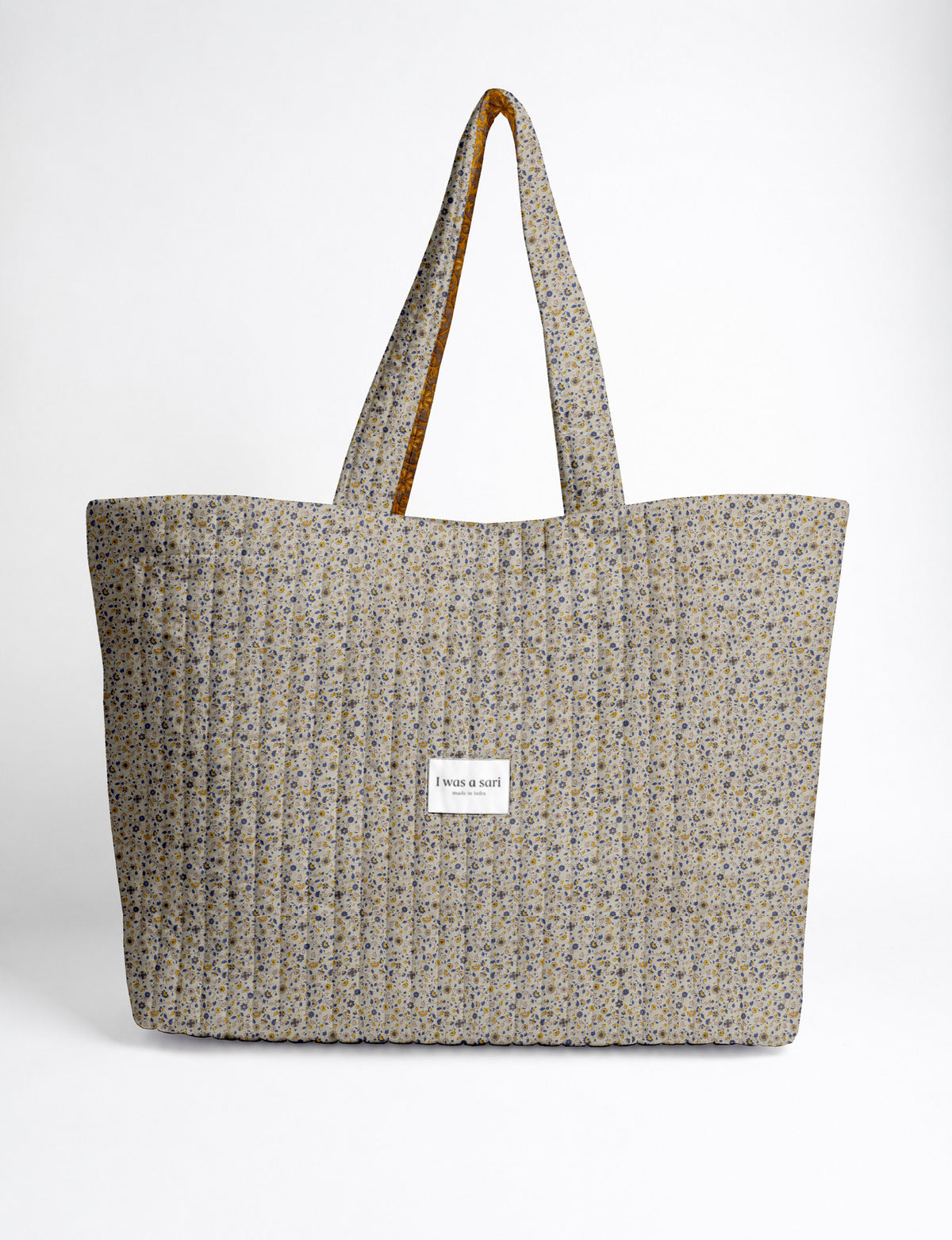 Quilted yellow tropical patterned beach bag with long handles and white label reading "I was a sari" front view