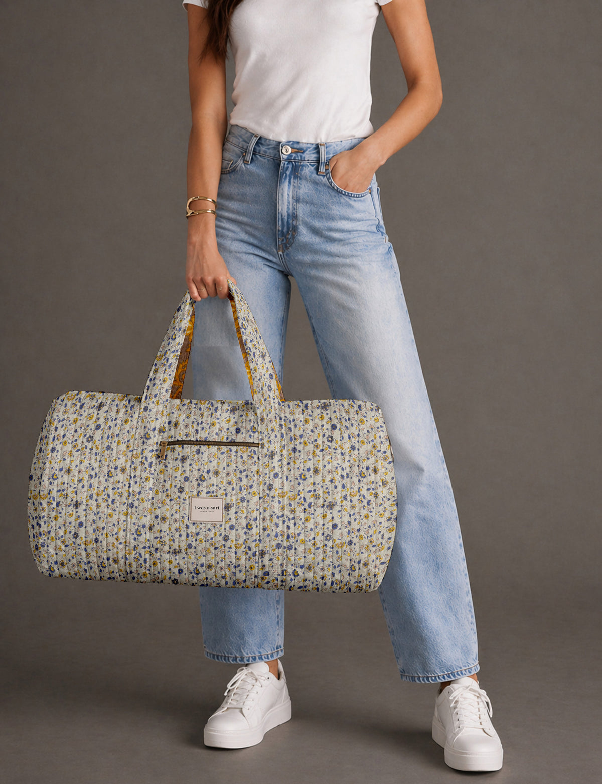 Quilted brown paisley barrel bag with double handles, front pocket, and gold zipper, shown in side angle view