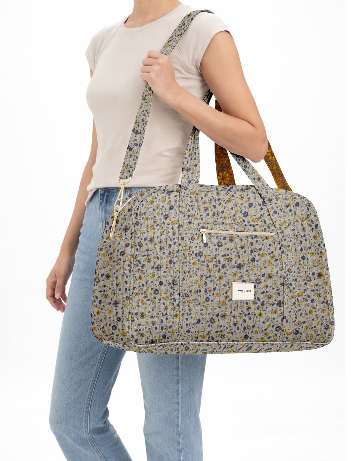 Brown quilted duffle bag with paisley pattern, front zip pocket, dual handles, and label reading "I was a sari"