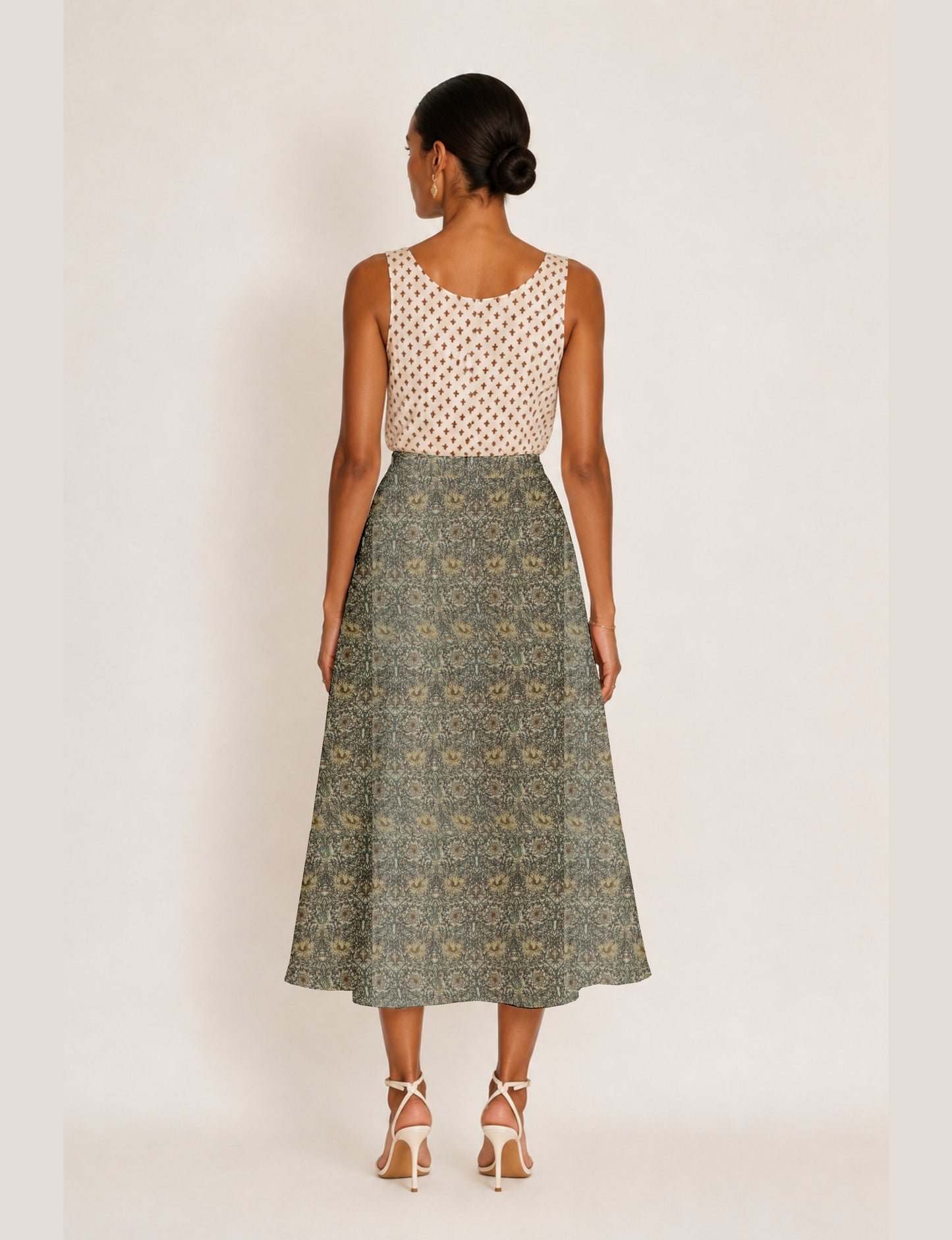 Woman wearing a yellow micro design A-line skirt with side slit, paired with a sleeveless beige top with small cross
