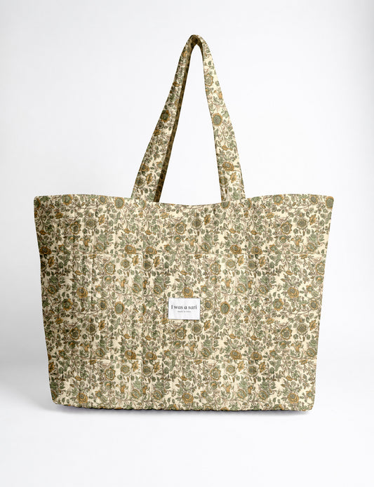 Quilted yellow tropical patterned beach bag with long handles and white label reading "I was a sari" front view