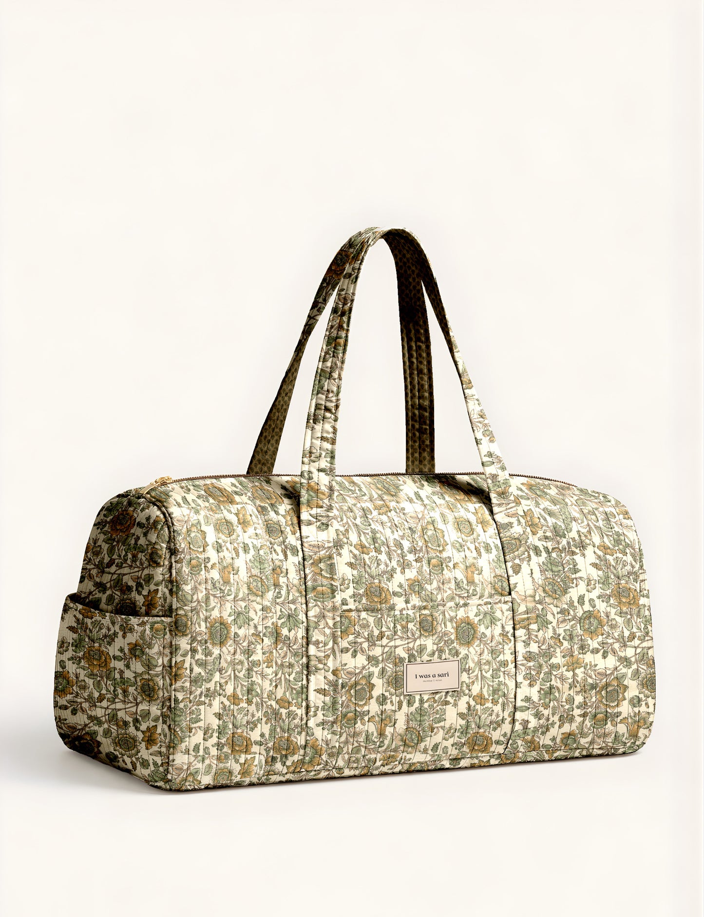 Quilted brown paisley barrel bag with double handles, front pocket, and gold zipper, shown in side angle view