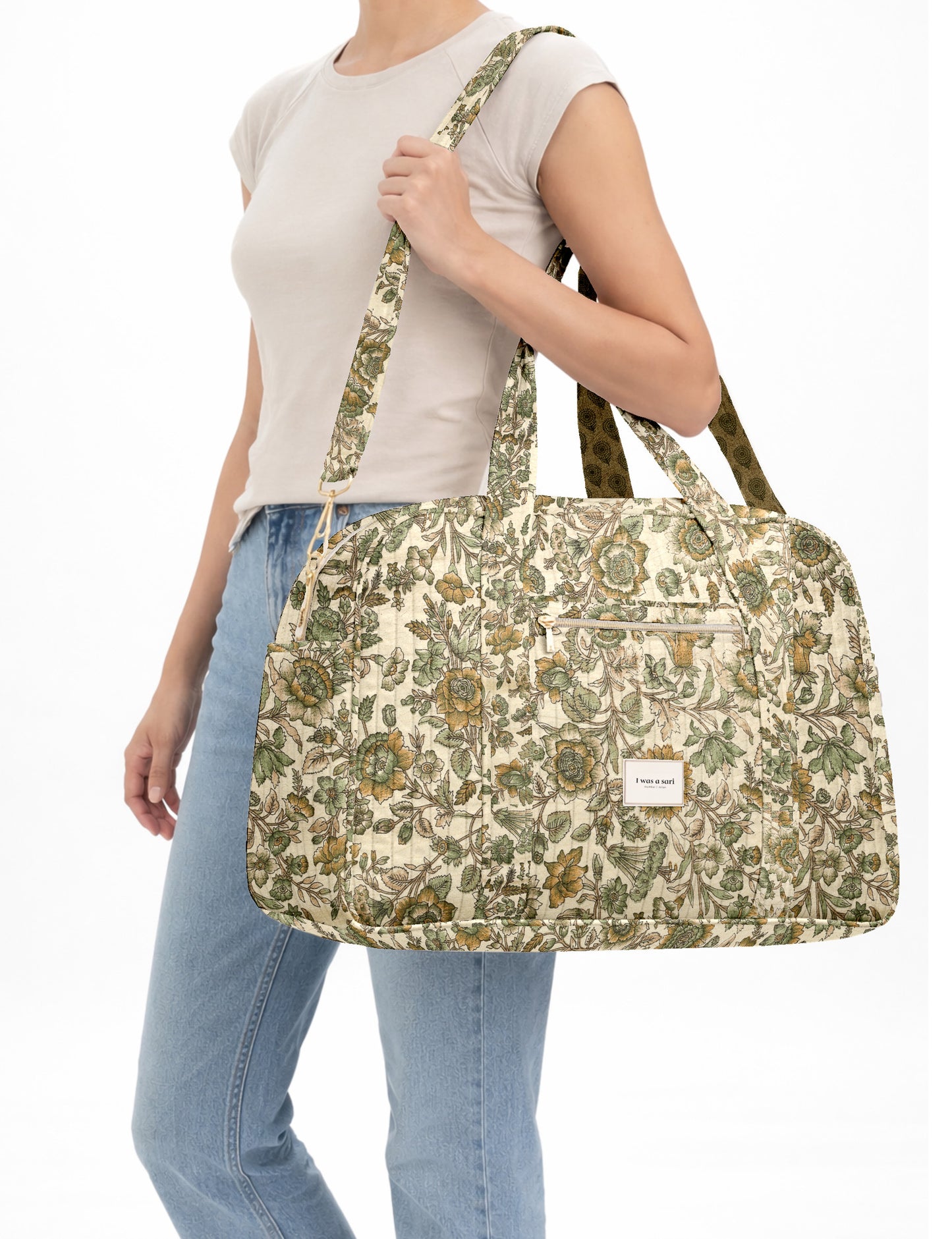 Brown quilted duffle bag with paisley pattern, front zip pocket, dual handles, and label reading "I was a sari"