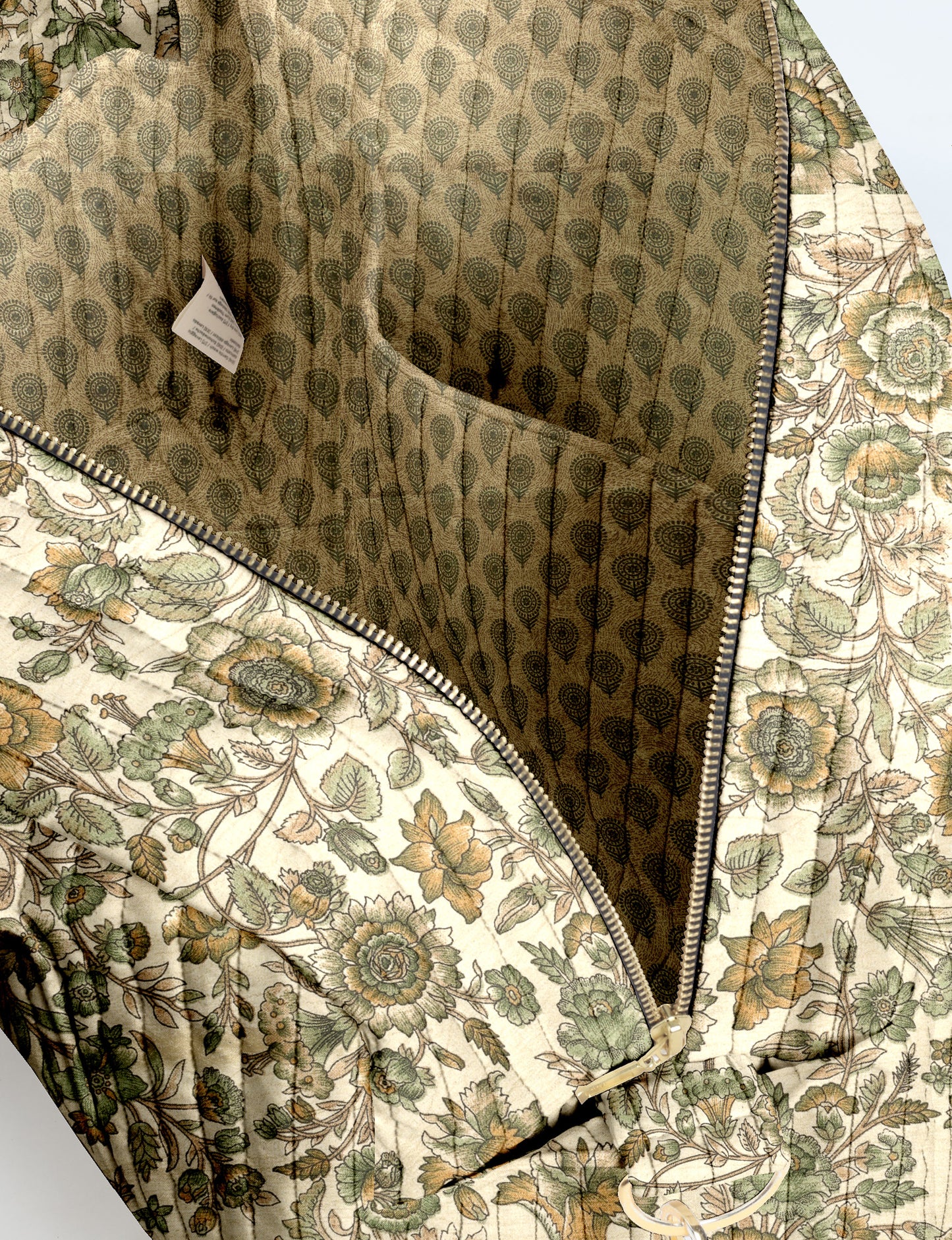Brown quilted duffle bag with paisley pattern, front zip pocket, dual handles, and label reading "I was a sari"