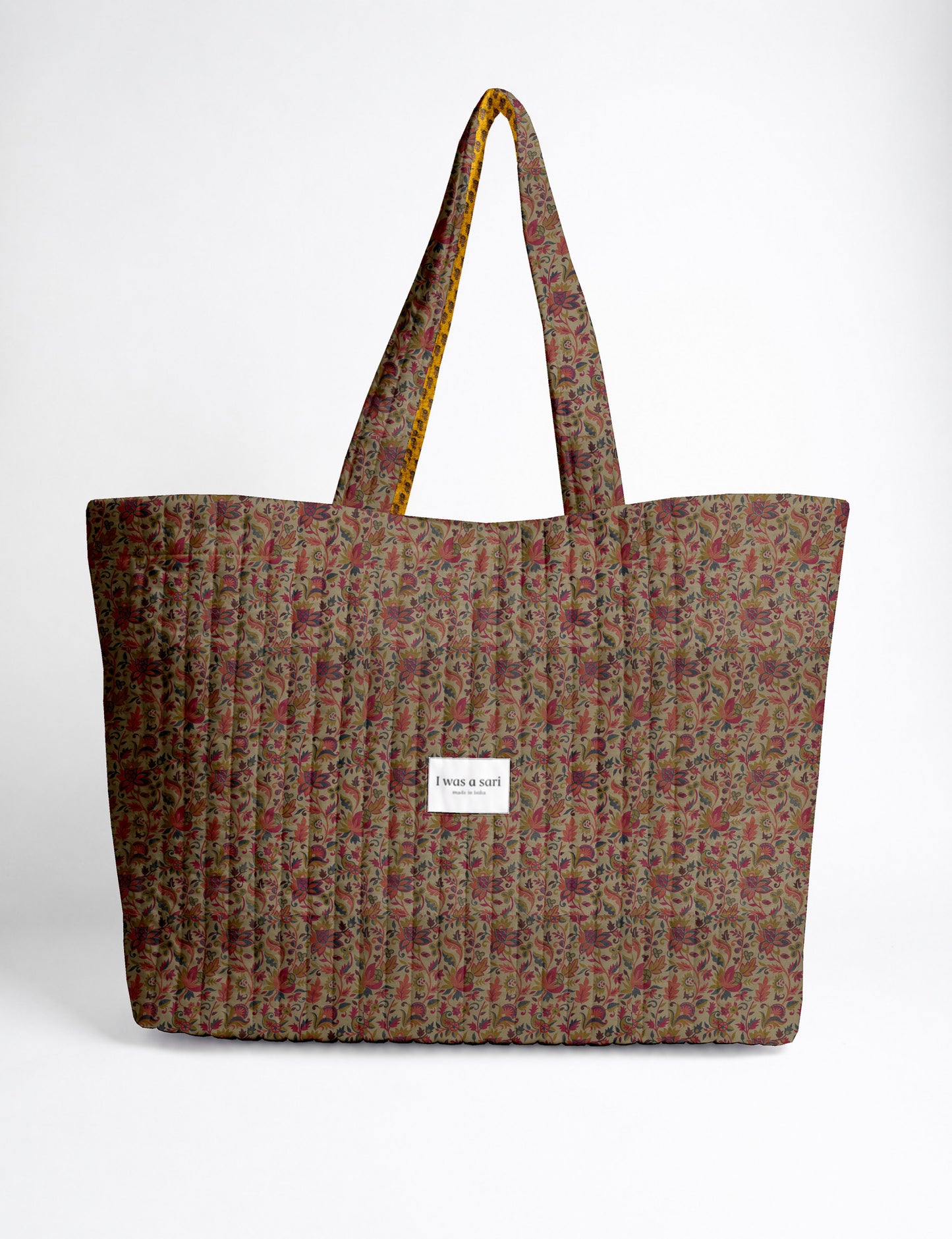 Quilted yellow tropical patterned beach bag with long handles and white label reading "I was a sari" front view