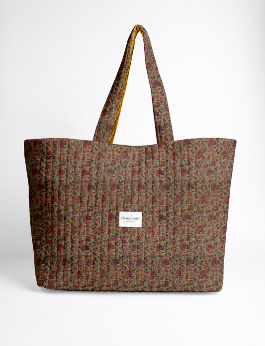 Quilted yellow tropical patterned beach bag with long handles and white label reading "I was a sari" front view