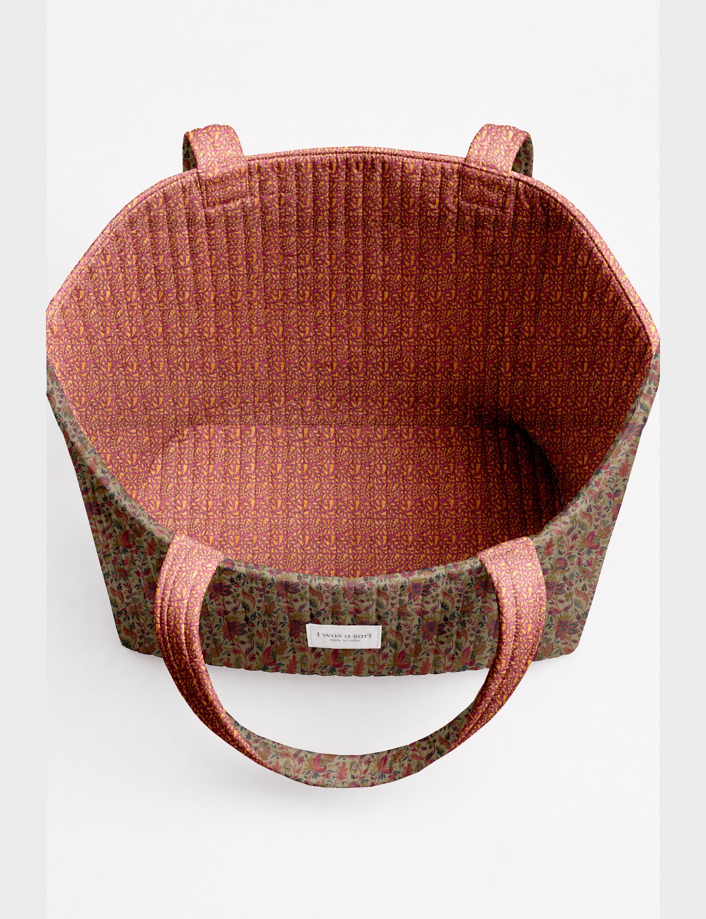 Quilted beach bag with yellow tropical exterior and red patterned interior, shown from top view with handles visible