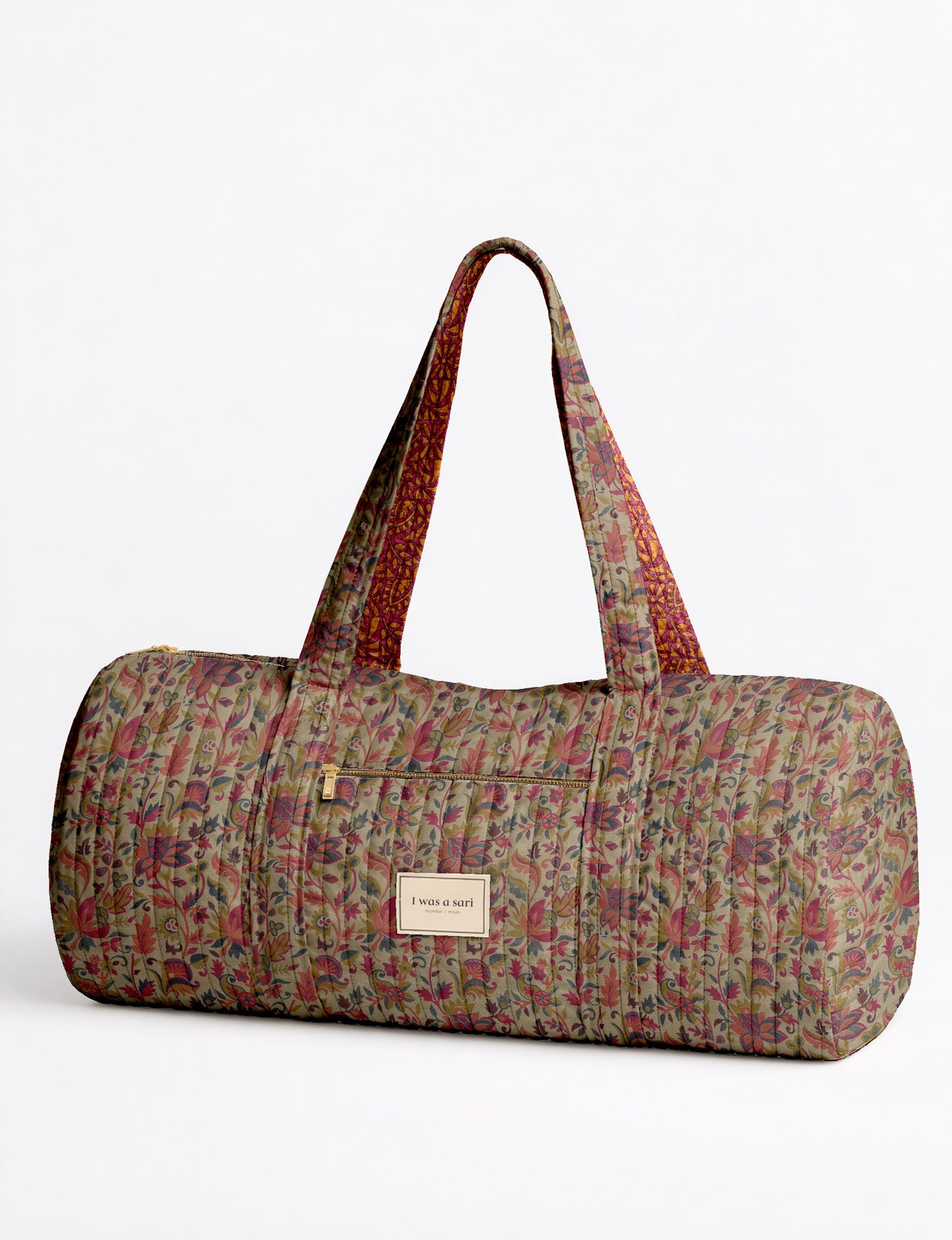 Brown paisley quilted bowling bag with front zipper pocket, held by person wearing white shirt and light blue jeans