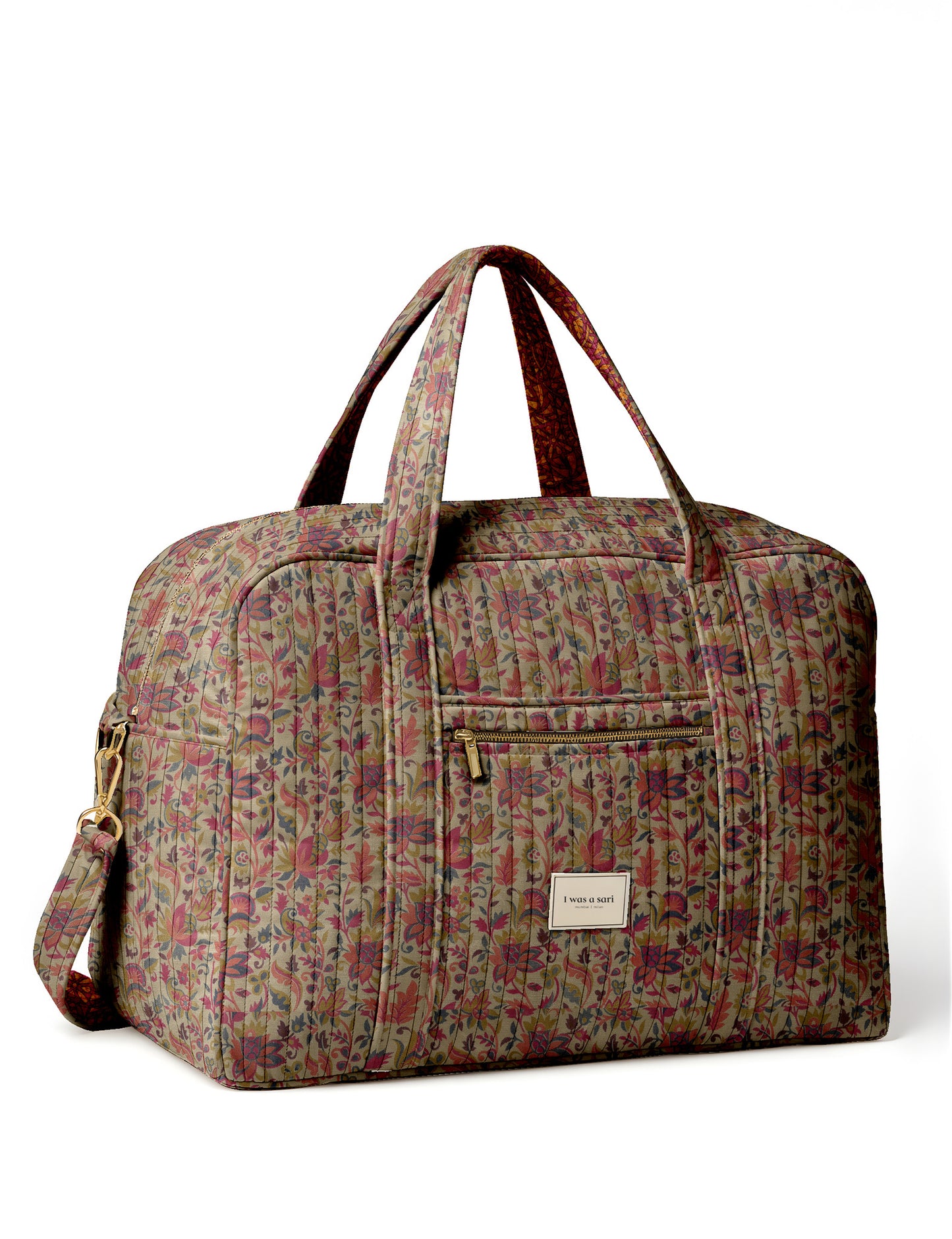Brown quilted duffle bag with paisley pattern, front zip pocket, dual handles, and label reading "I was a sari"
