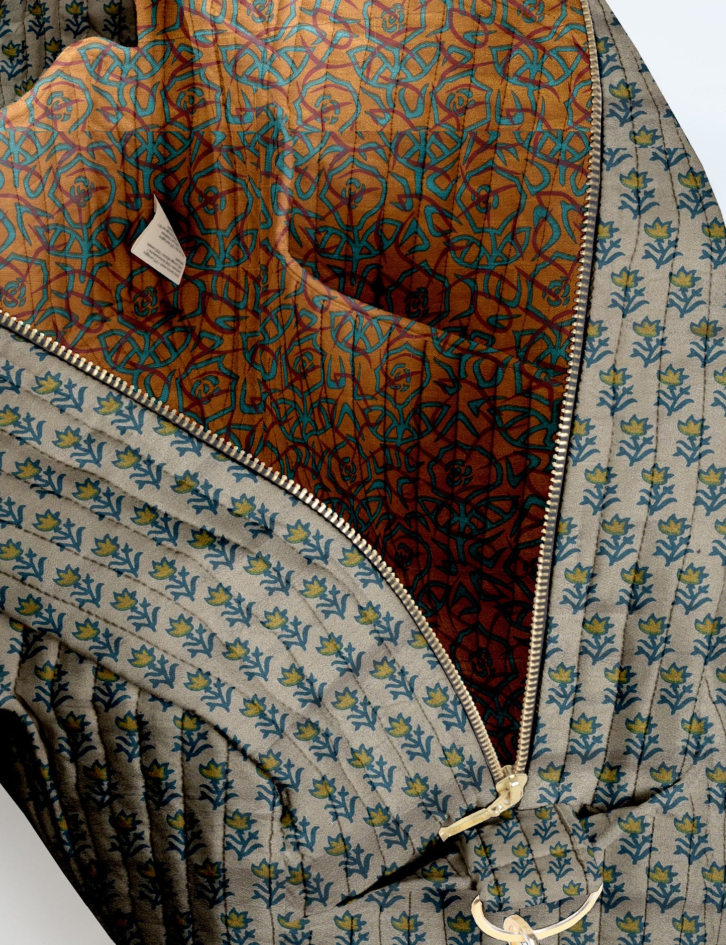 Brown quilted duffle bag with paisley pattern, front zip pocket, dual handles, and label reading "I was a sari"
