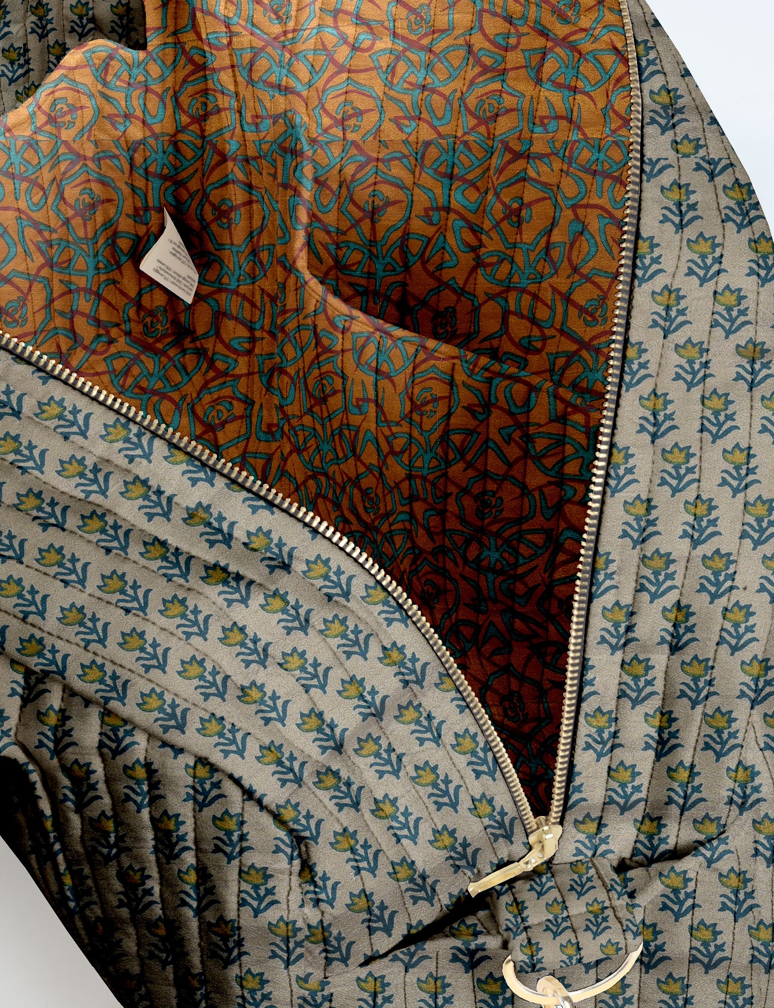 Brown quilted duffle bag with paisley pattern, front zip pocket, dual handles, and label reading "I was a sari"