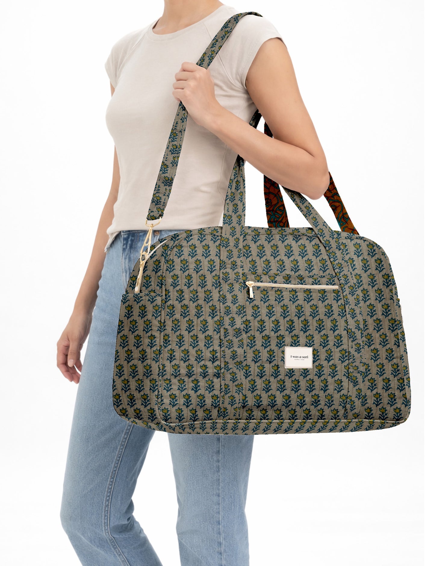 Brown quilted duffle bag with paisley pattern, front zip pocket, dual handles, and label reading "I was a sari"