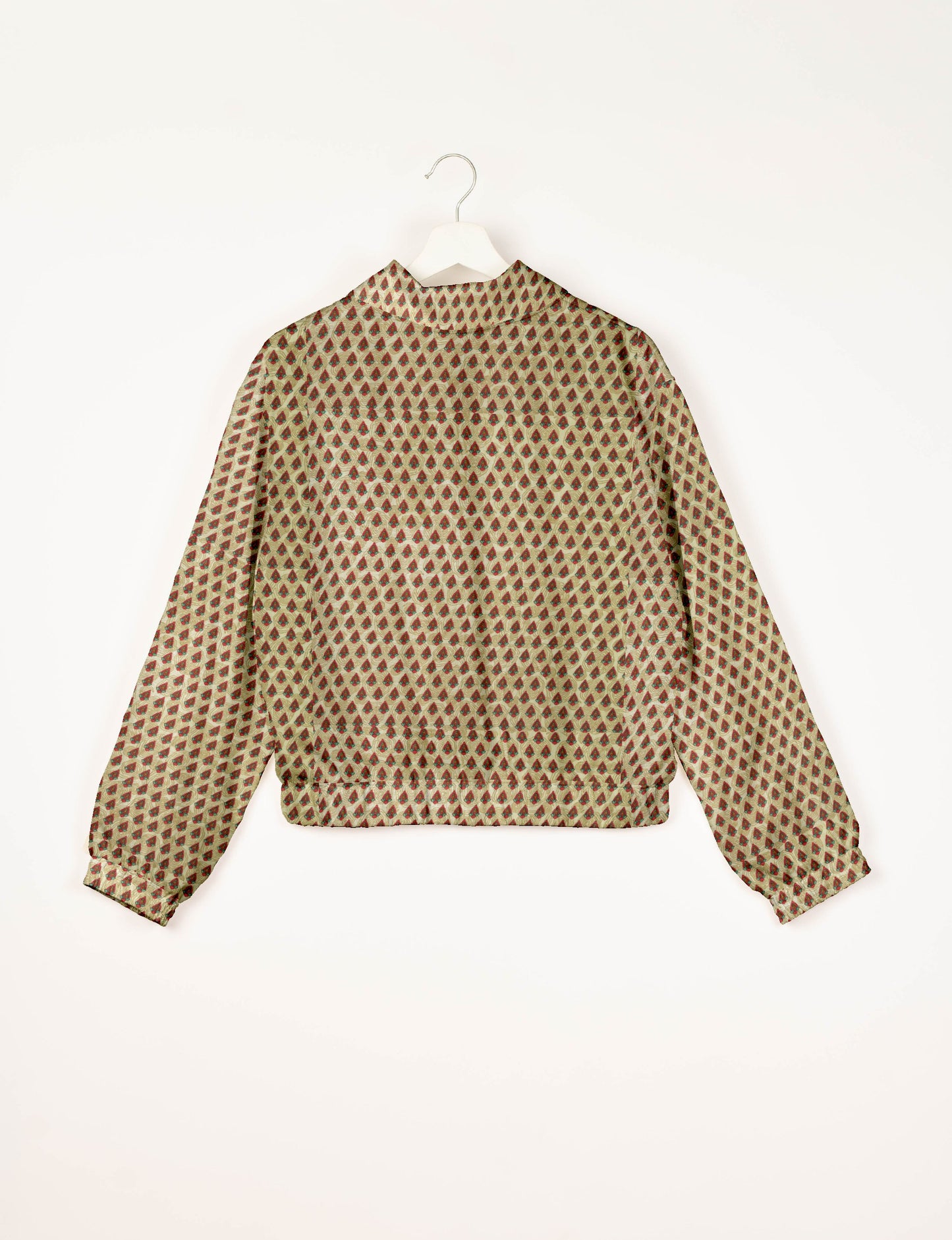 Beige bomber jacket with red and green Indian ethnic print, long sleeves, elastic cuffs and waistband, back view on hanger