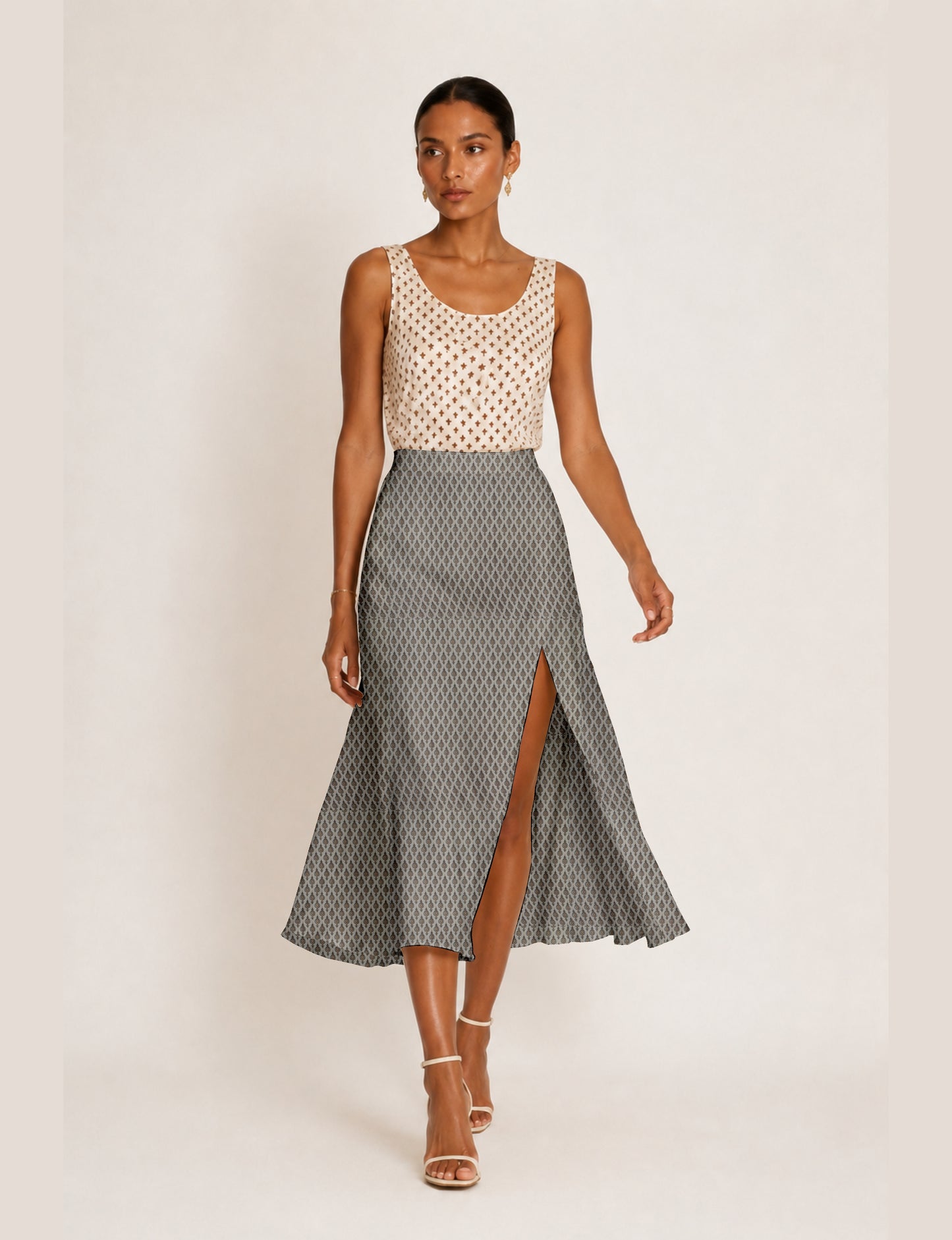 Woman wearing a yellow and black micro patterned A-line skirt with front slit, paired with beige sleeveless top and black