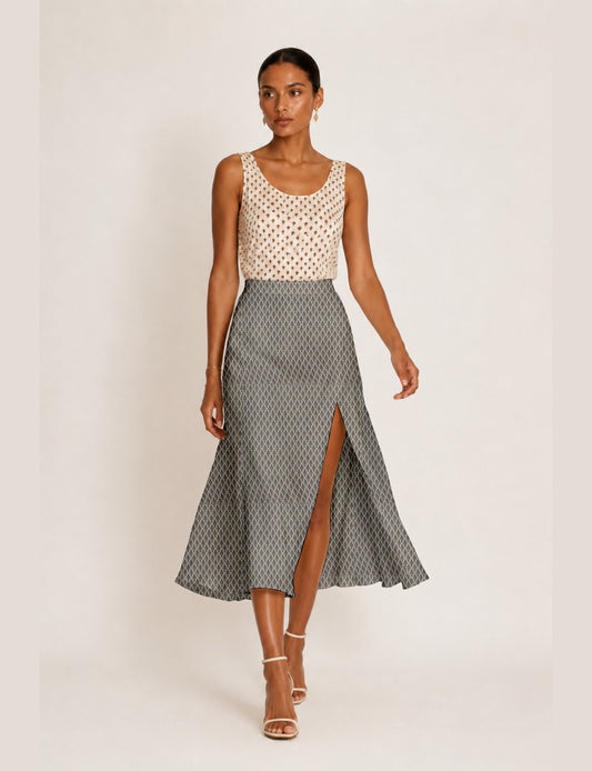 Woman wearing a yellow and black micro patterned A-line skirt with front slit, paired with beige sleeveless top and black