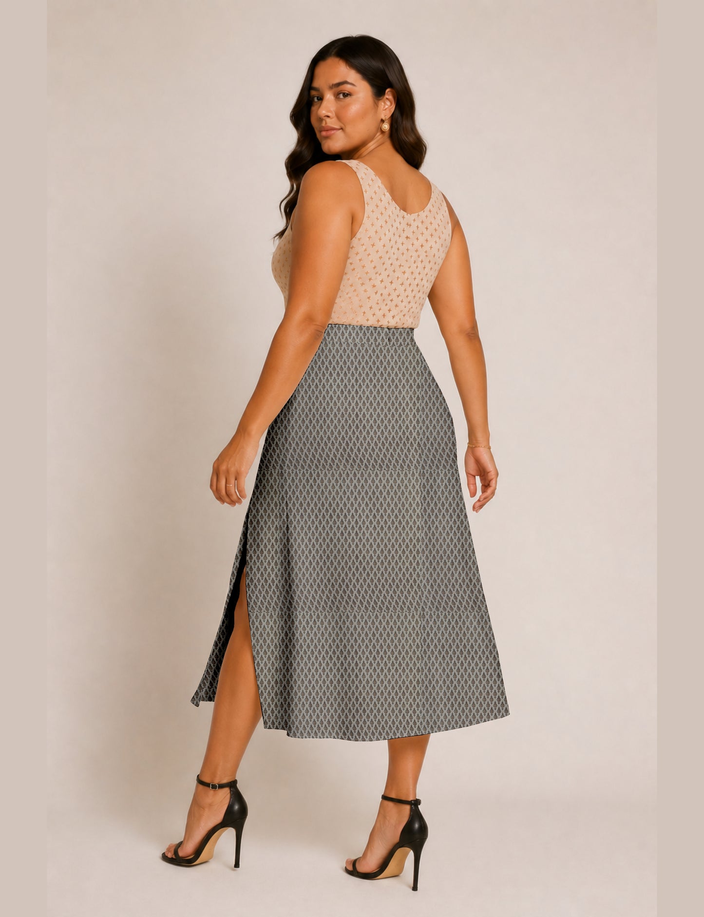 Woman wearing a yellow and black micro patterned A-line skirt with front slit, paired with beige sleeveless top and black