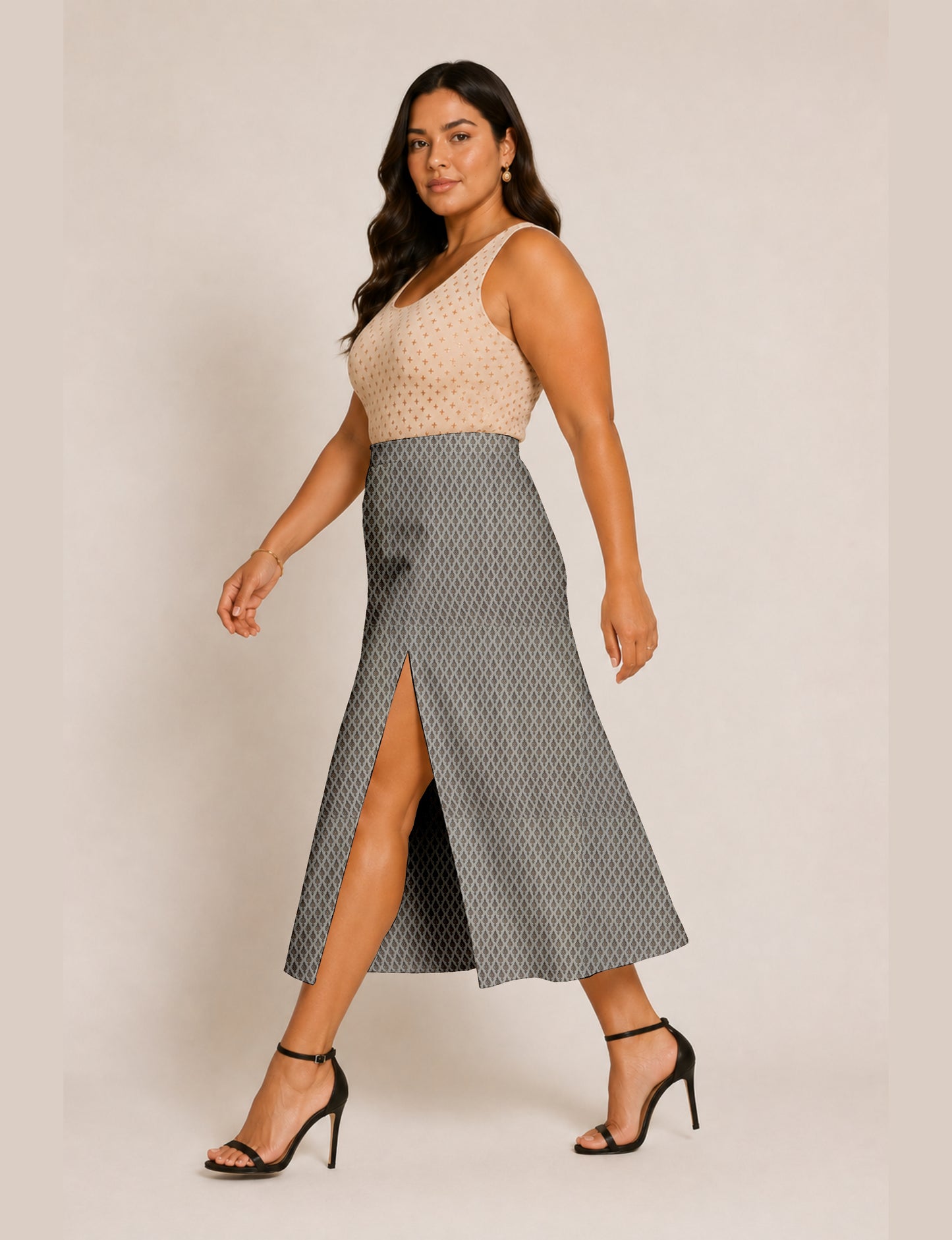 Woman wearing a yellow and black micro patterned A-line skirt with front slit, paired with beige sleeveless top and black