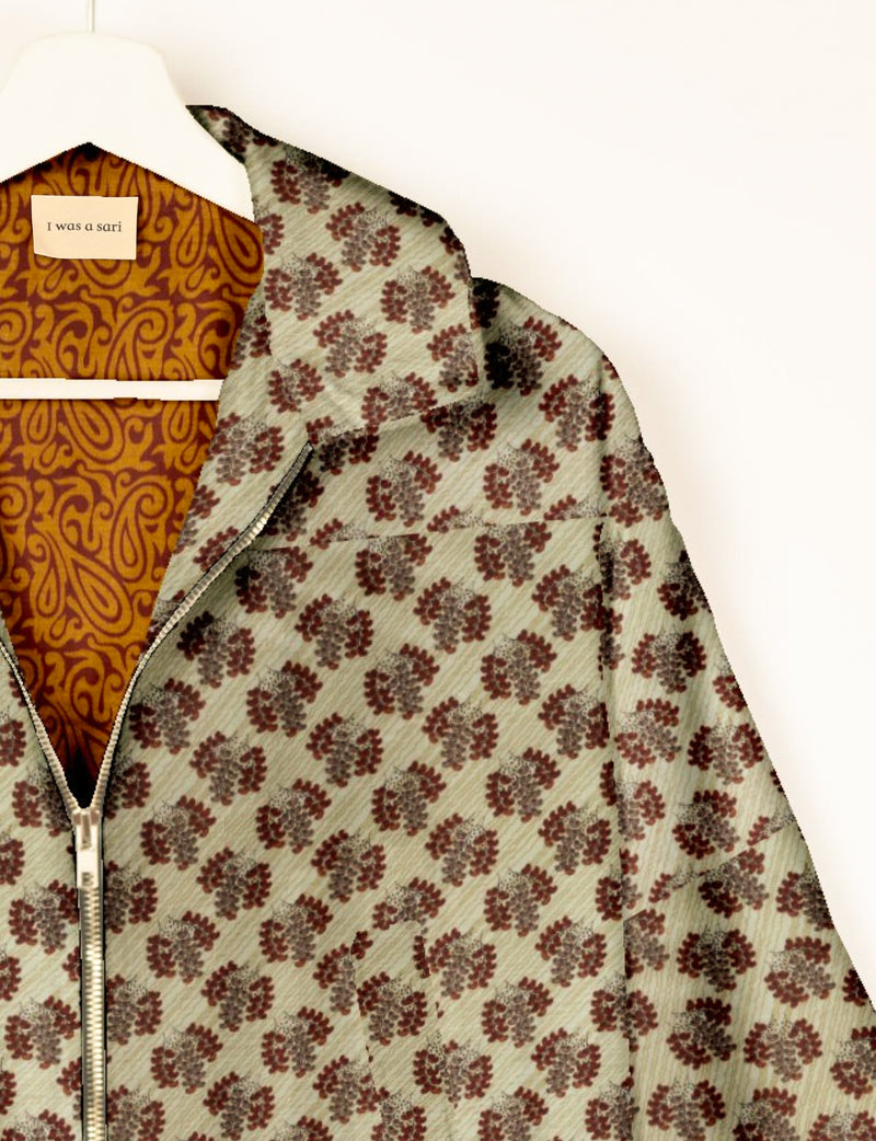 Beige bomber jacket with brown leaf pattern, front zipper, and orange paisley patterned lining on hanger with "I was a sari"
