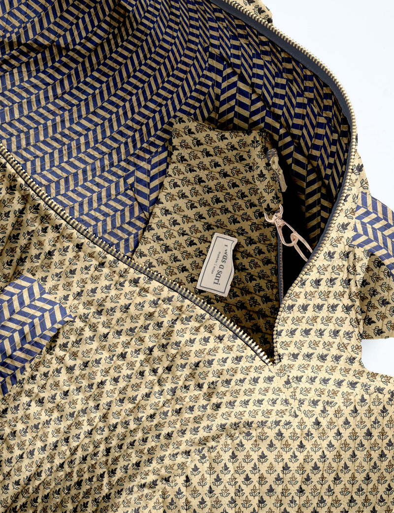 Beige quilted bowling bag with micro floral print exterior and blue geometric patterned interior, open zipper view