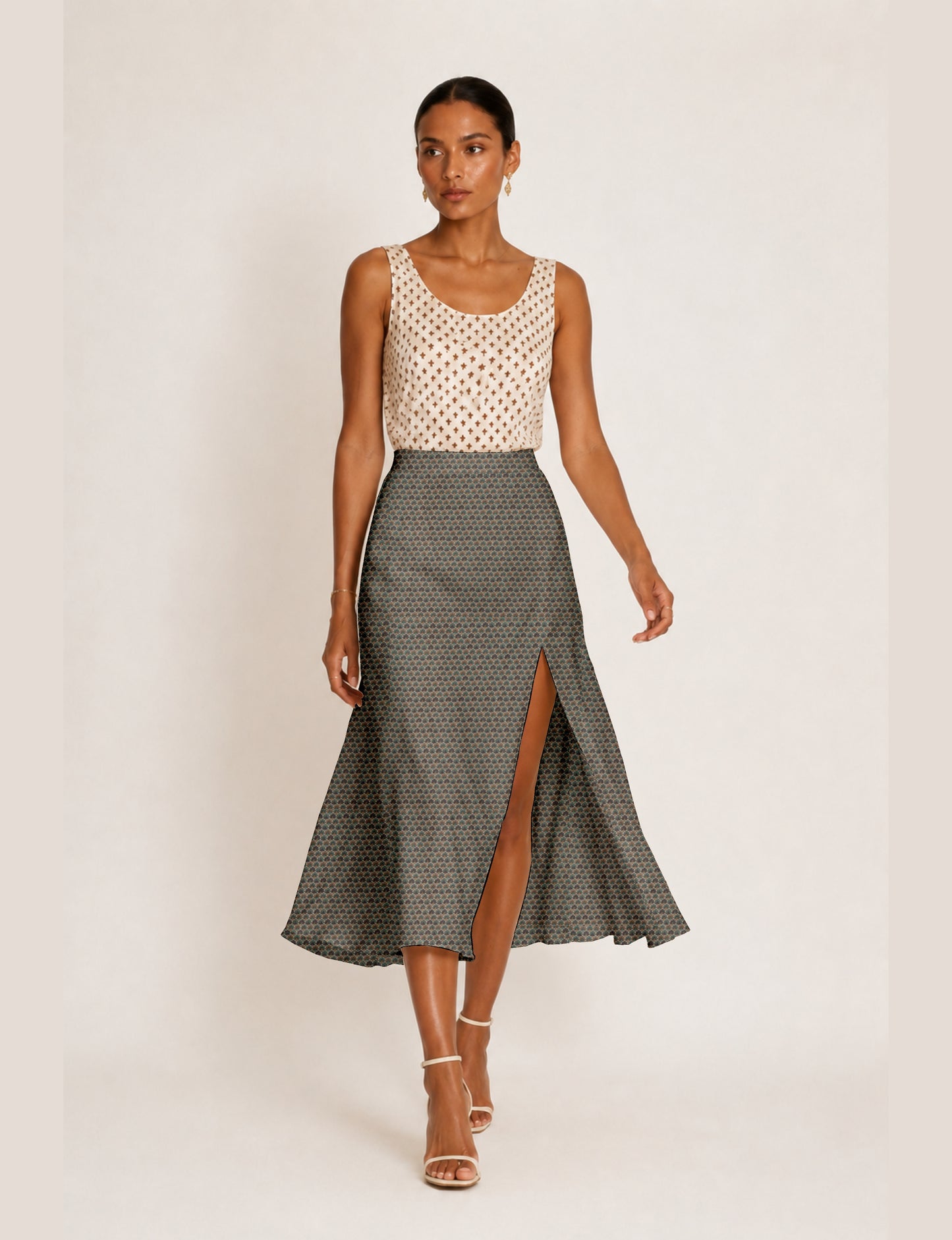 Woman wearing a yellow and black micro patterned A-line skirt with front slit, paired with beige sleeveless top and black