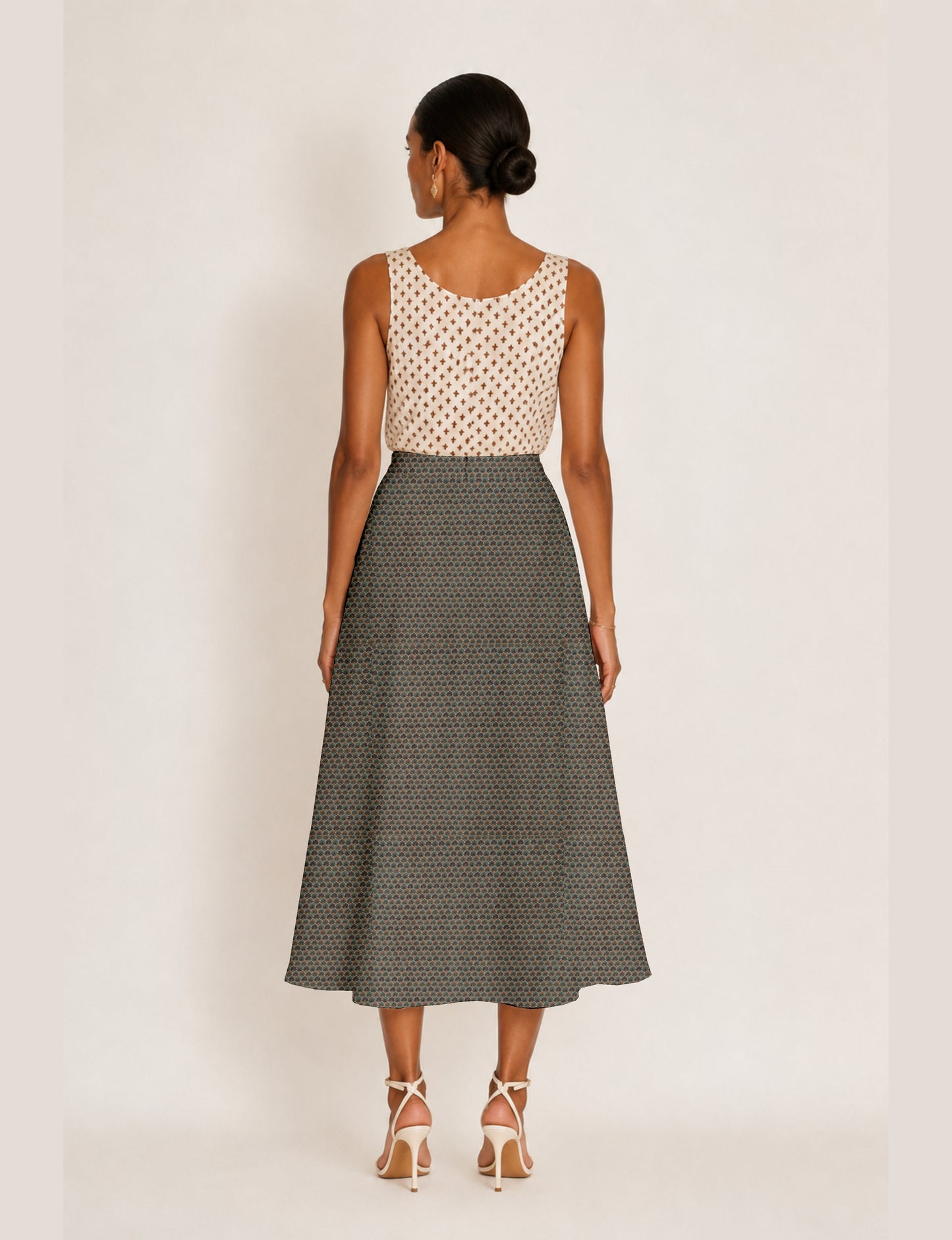 Woman wearing a yellow and black micro patterned A-line skirt with front slit, paired with beige sleeveless top and black