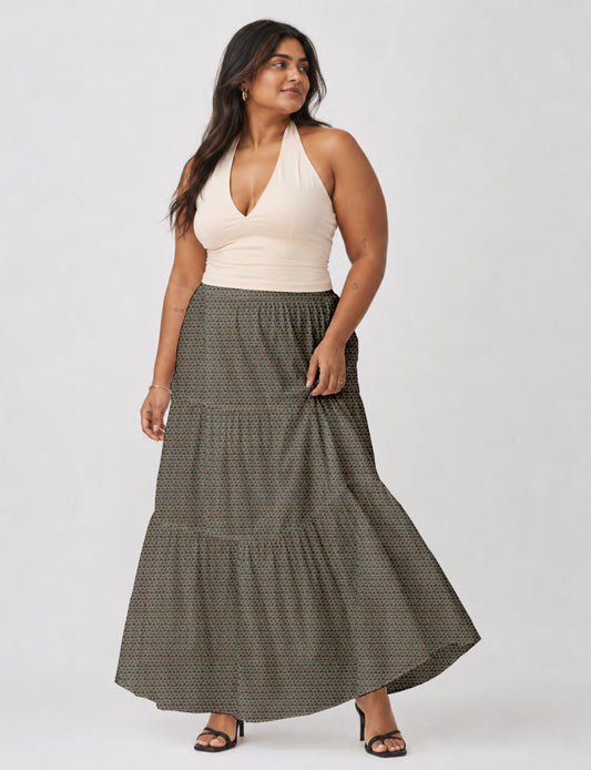 Woman wearing a yellow midi tiered skirt with a small geometric pattern, paired with a beige strapless top and white heels