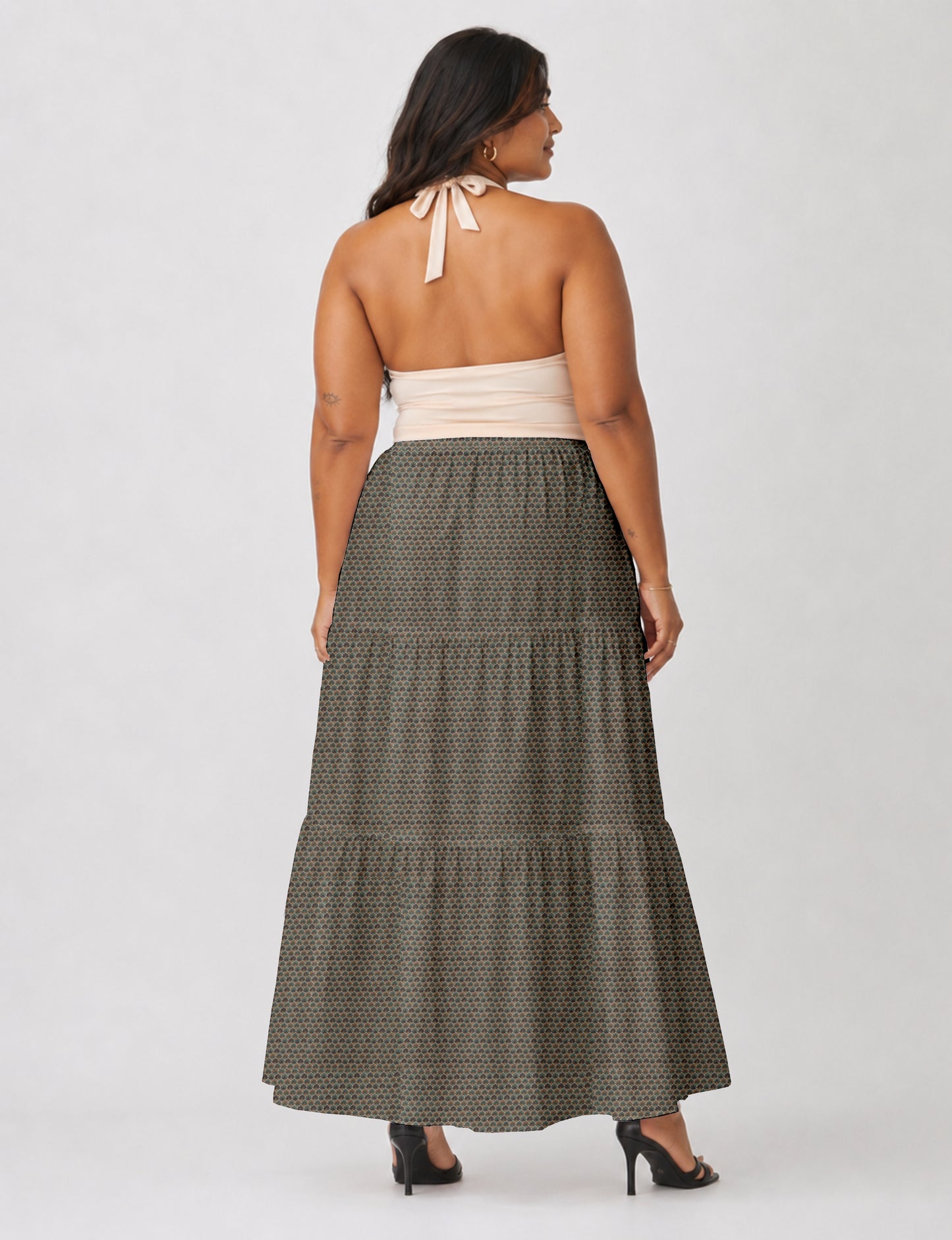 Woman wearing a yellow midi tiered skirt with a small geometric pattern, shown from the back, paired with beige top and