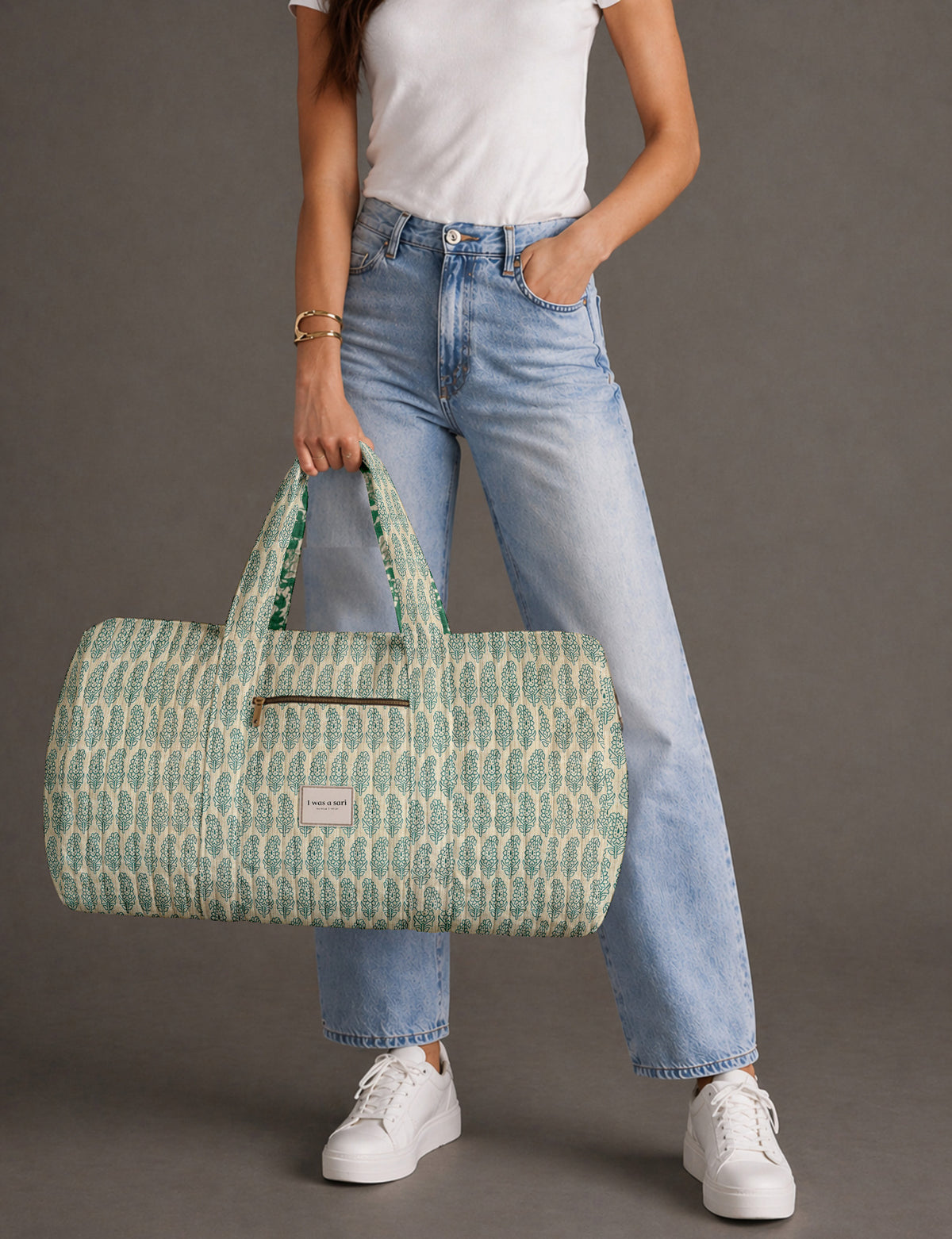 Quilted brown paisley barrel bag with double handles, front pocket, and gold zipper, shown in side angle view