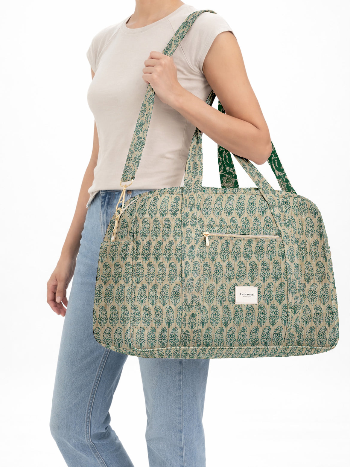 Brown quilted duffle bag with paisley pattern, front zip pocket, dual handles, and label reading "I was a sari"