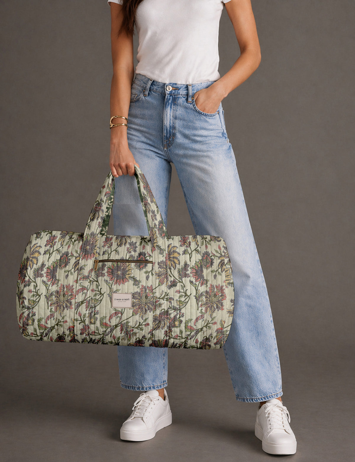 Quilted brown paisley barrel bag with double handles, front pocket, and gold zipper, shown in side angle view