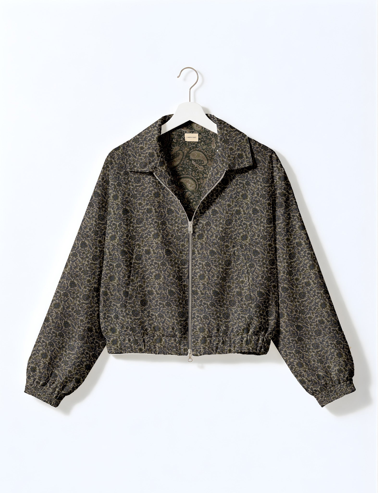 Brown floral bomber jacket with front zipper, elastic cuffs and hem, hanging on white hanger, red floral inner lining visible