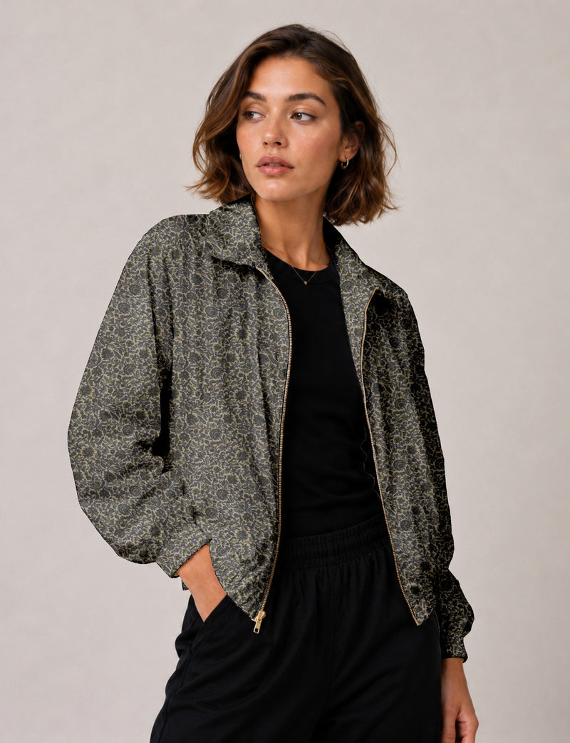 Woman wearing a yellow floral bomber jacket with front zipper, elastic cuffs, and side pockets, shown from front view