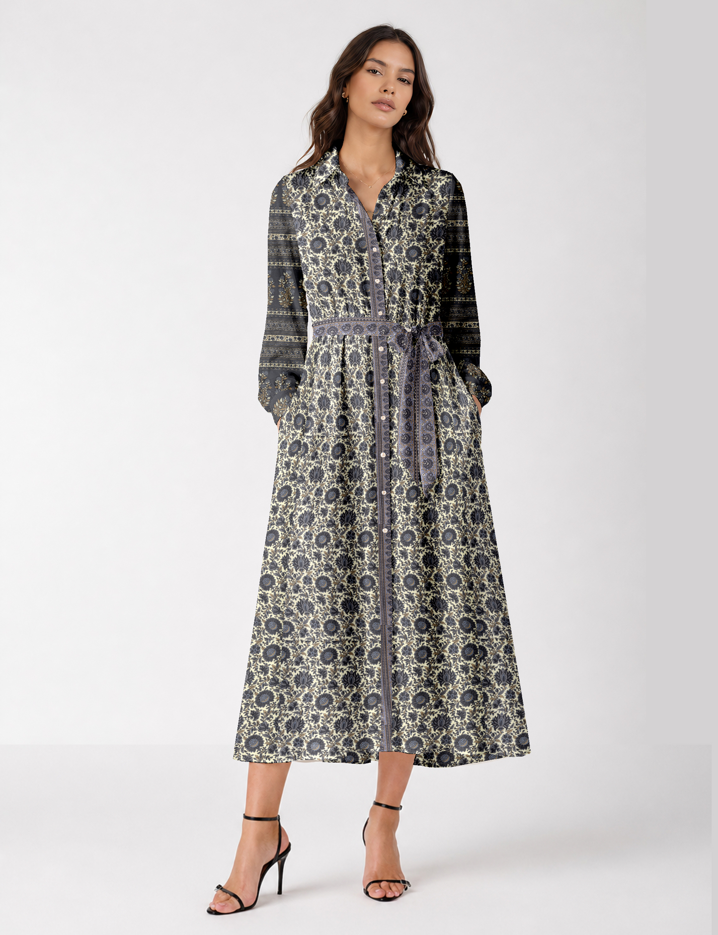 Woman wearing a long button-up shirt dress with beige and black floral and striped patterns, tied at the waist with a