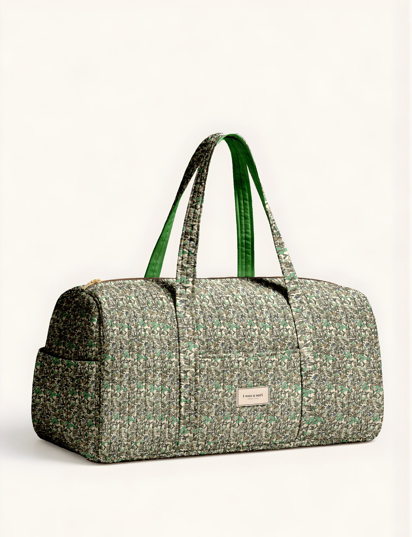 Quilted brown paisley barrel bag with double handles, front pocket, and gold zipper, shown in side angle view