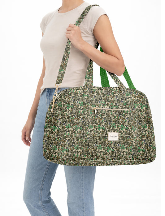Brown quilted duffle bag with paisley pattern, front zip pocket, dual handles, and label reading "I was a sari"