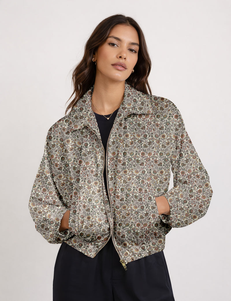 Woman wearing a yellow floral bomber jacket with front zipper, elastic cuffs, and side pockets, shown from front view