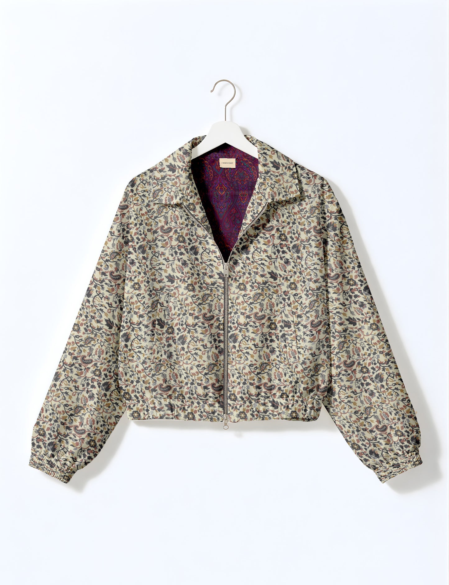 Brown floral bomber jacket with front zipper, elastic cuffs and hem, hanging on white hanger, red floral inner lining visible