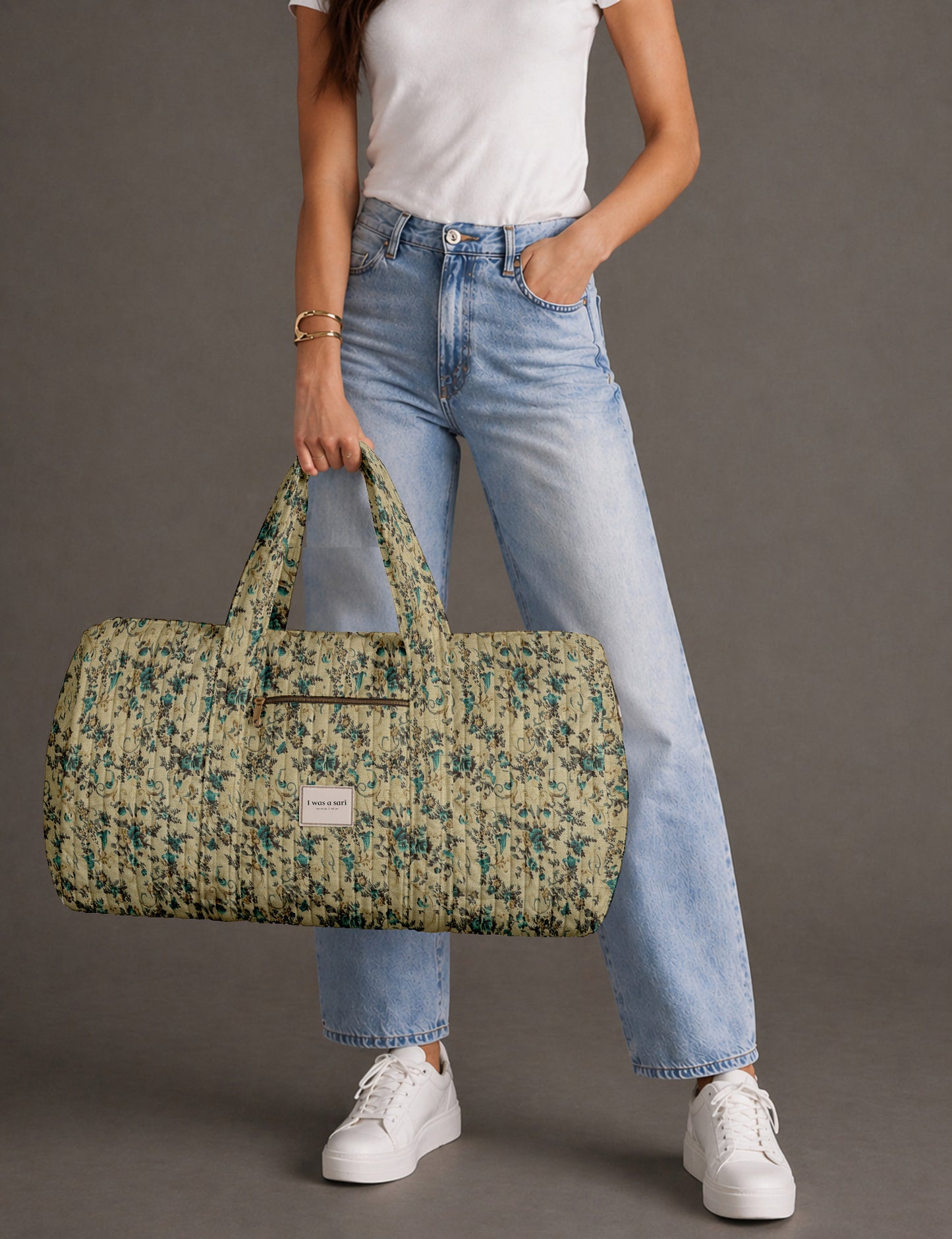 Quilted brown paisley barrel bag with double handles, front pocket, and gold zipper, shown in side angle view