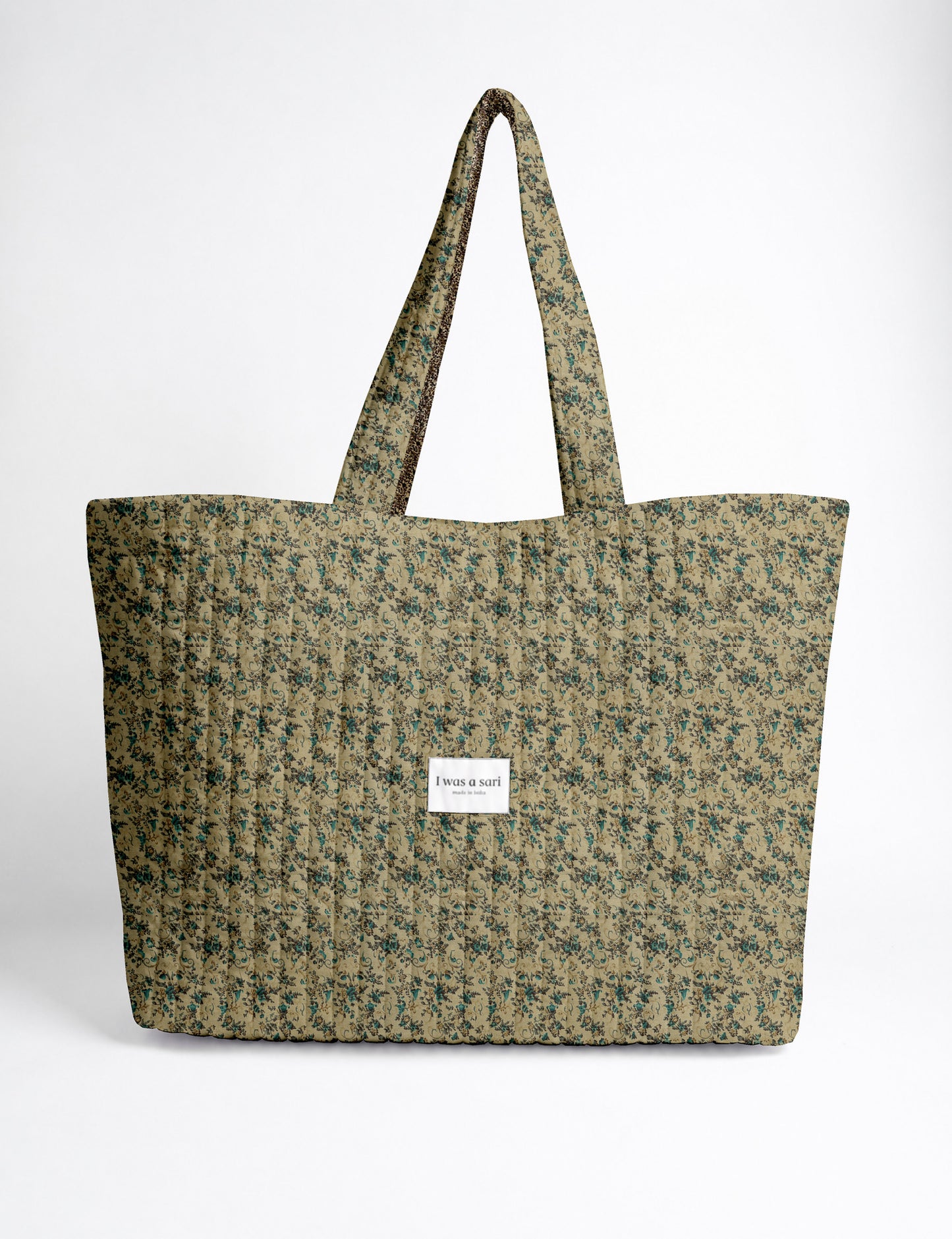 Quilted yellow tropical patterned beach bag with long handles and white label reading "I was a sari" front view