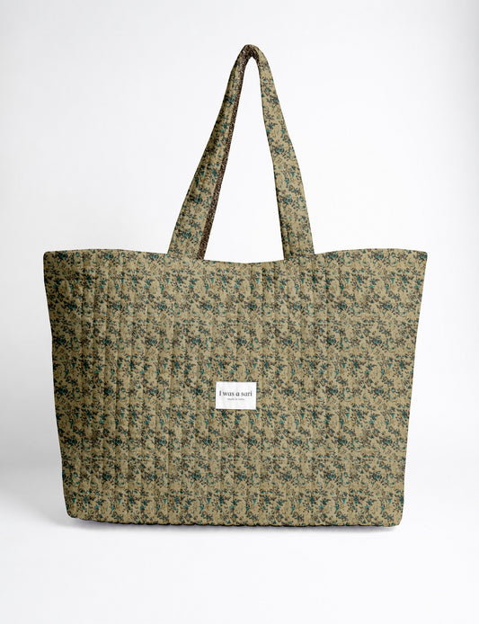 Quilted yellow tropical patterned beach bag with long handles and white label reading "I was a sari" front view